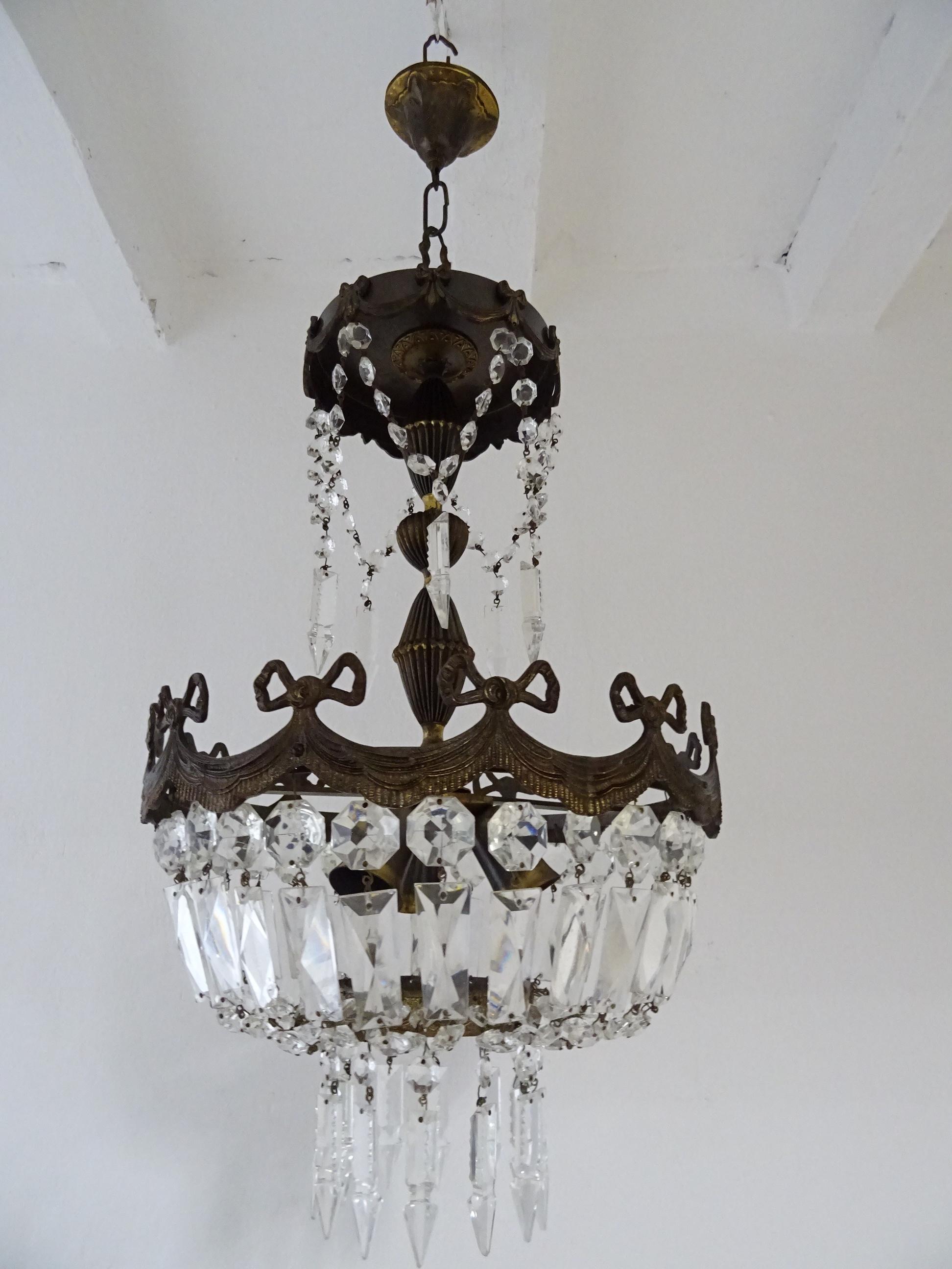 This chandelier will be newly rewired with certified US UL sockets for the USA and appropriate sockets for all other countries.  Housing 3 lights. . Bronze bows detail with great patina.   Crystal prisms, all intact. Adding 8  inches of original