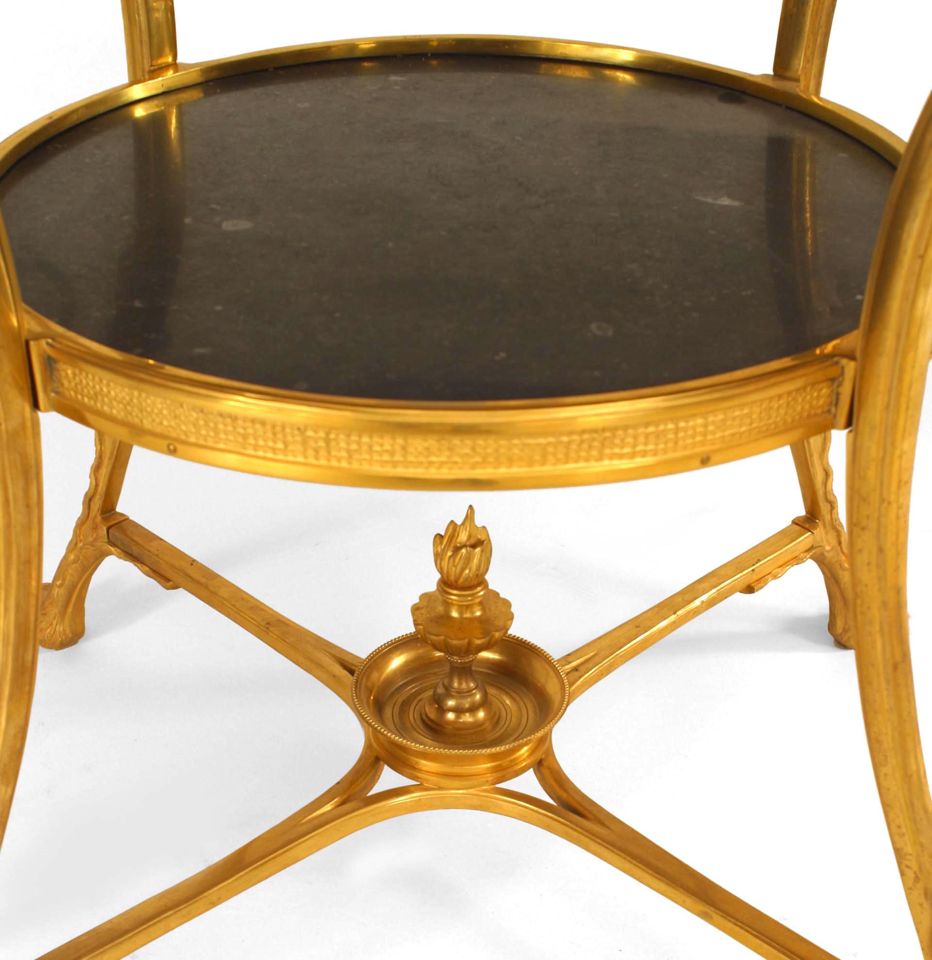 Table d'appoint de style Empire français en bronze à 4 pieds terminés par des têtes de lion tenant des anneaux avec un plateau rond en marbre noir et une étagère.