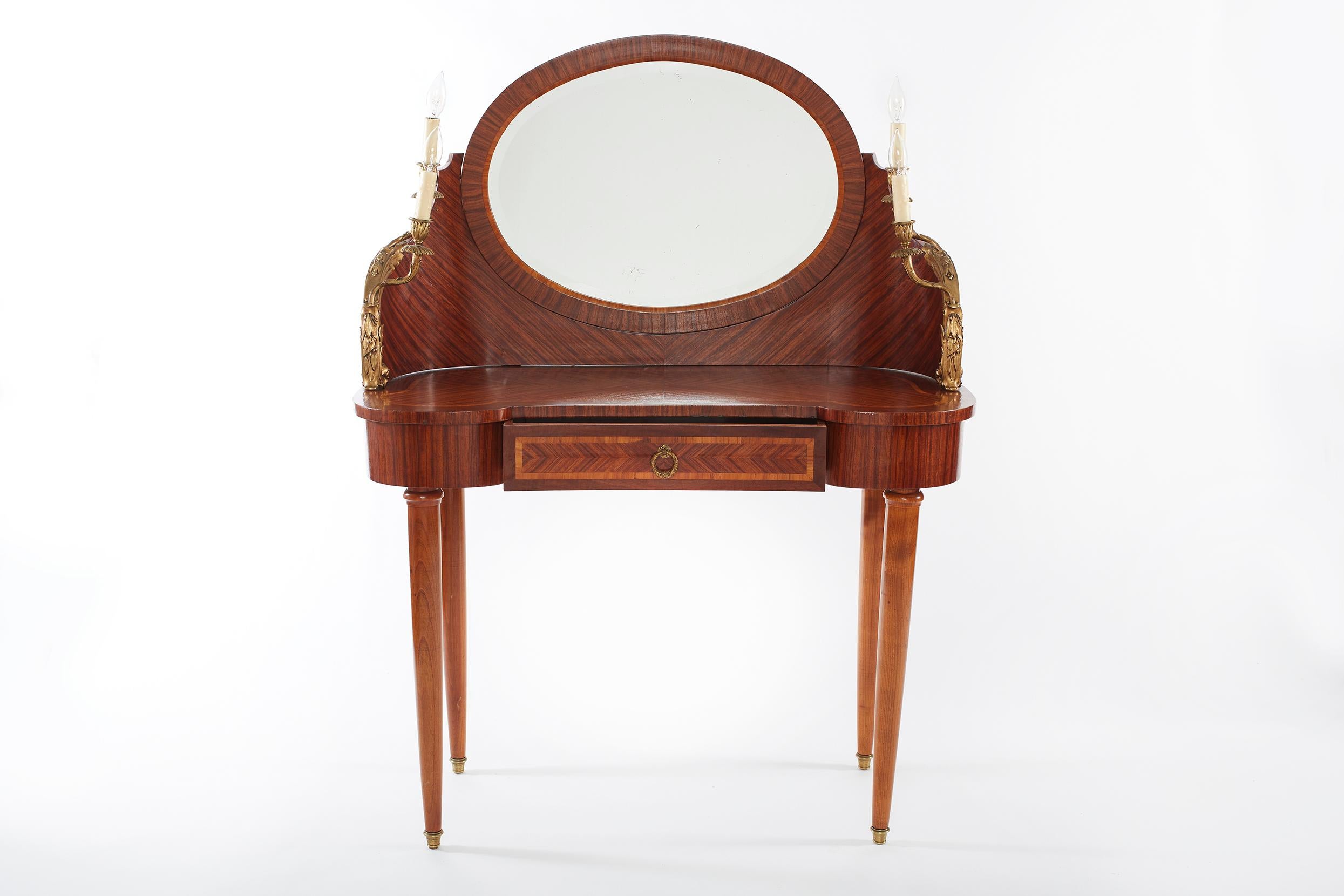 French Empire style mahogany vanity / dressing table with gilt bronze mounted design and oval attached mirror, front pulling drawer and side pair of candelabra. The vanity / dressing table is in great condition. Minor wear consistent with age / use.