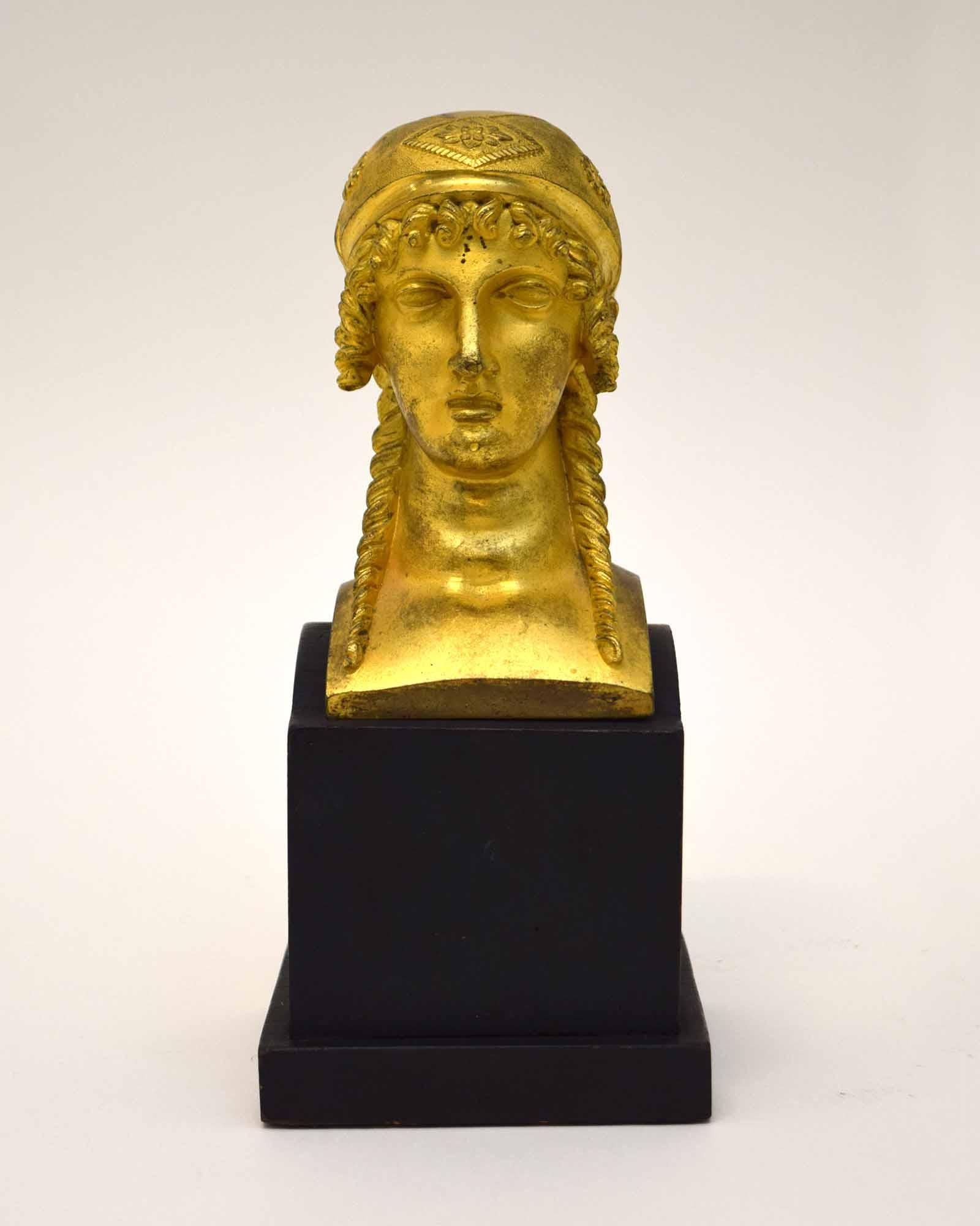This Empire ormolu head of a woman was made as a furniture mount in France around 1810, and probably adorned a bed. In any case, closer to our own time, it was deemed worthy of mounting as a sculpture on a finely made base. Its neoclassical style,