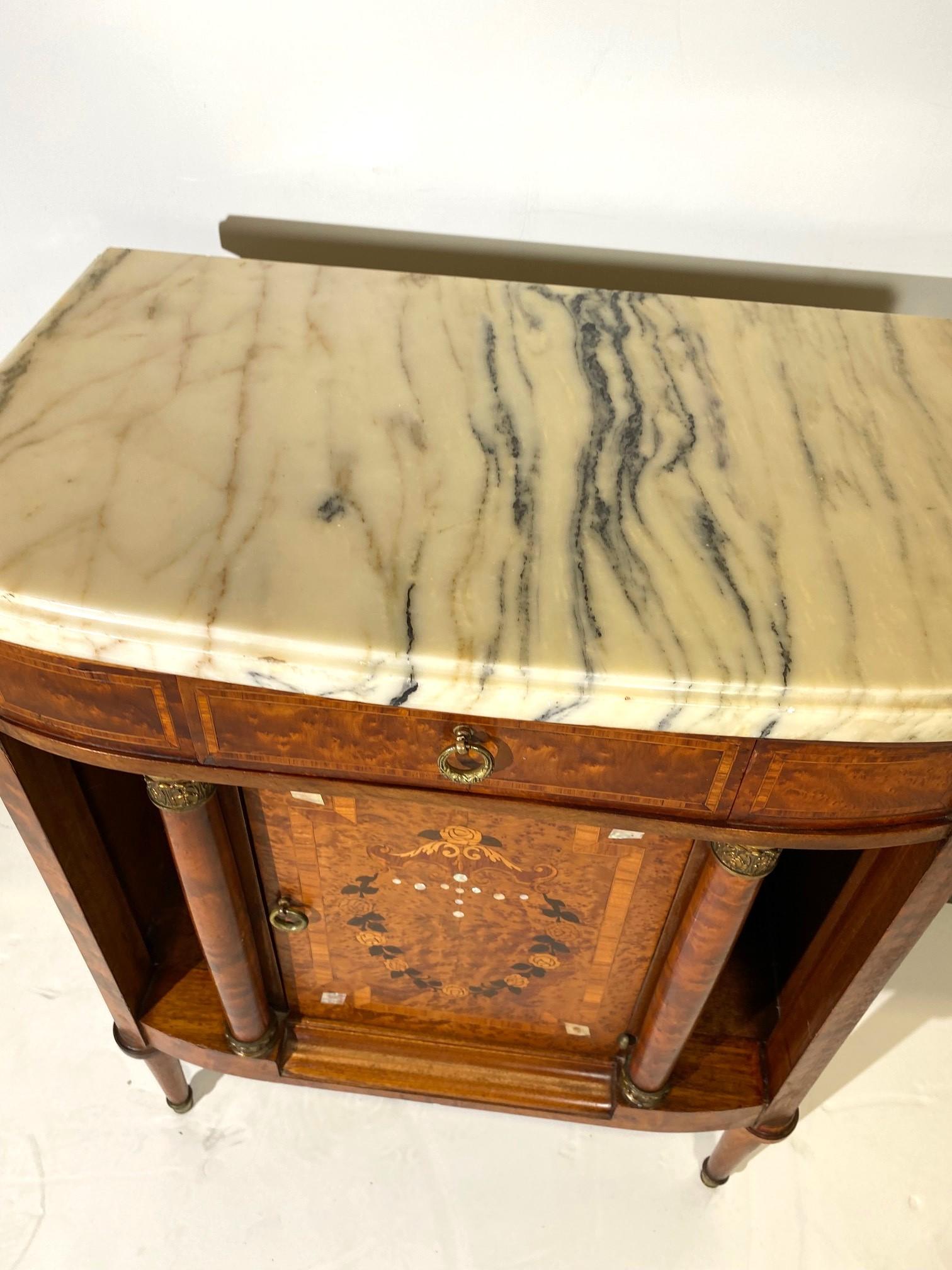 French Empire marble top cabinet. Center door with a burlwood marquetry panel showing floral decoration of mother-of-pearl inlays. Kingwood crossbanding to the drawers and doors. Pillars fitted with gilt metal mounts in classical design. c1900 