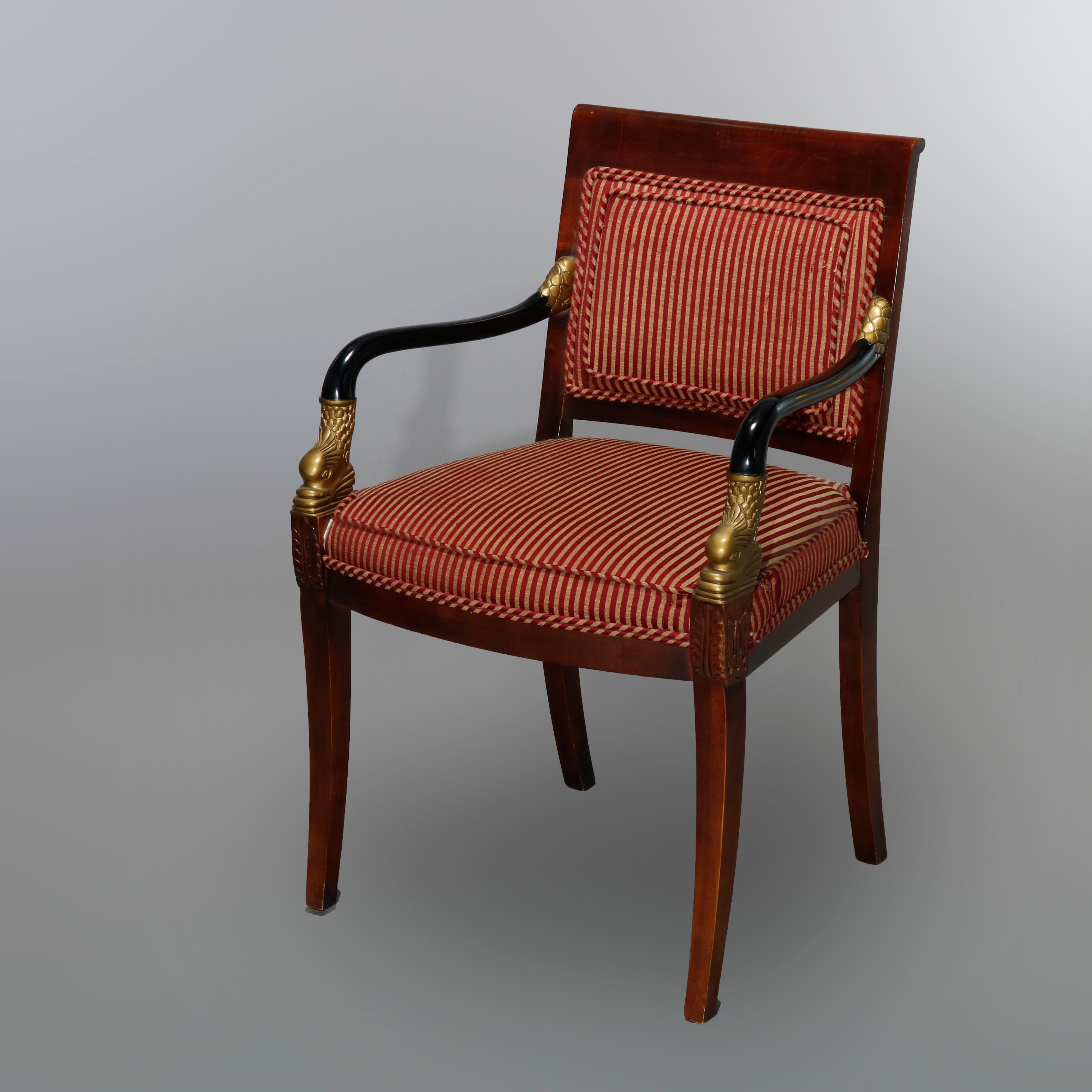 An antique pair of French Empire armchairs by Century Chair Co., Hickory, NC offer mahogany frames with ebonized arms having carved and gilt dolphins, backs and seats upholstered in striped fabric, maker label as photographed, 20th