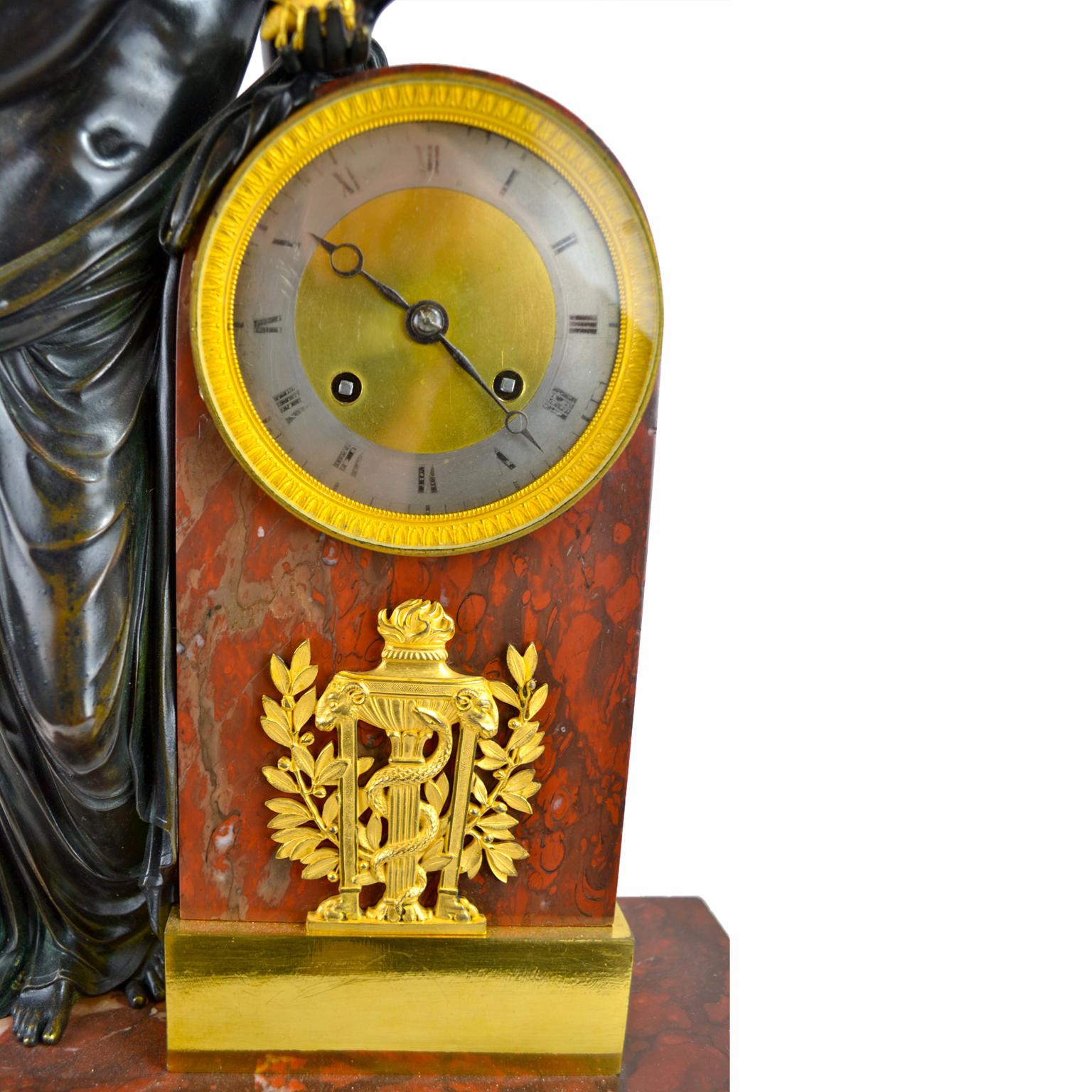 A French Empire Clock depicting Psyche playing with a butterfly after a marble statue by Canova displayed in the Louvre. A patinated bronze Psyche is standing to the left of the clock plinth holding a butterfly in her left hand and the butterfly’s