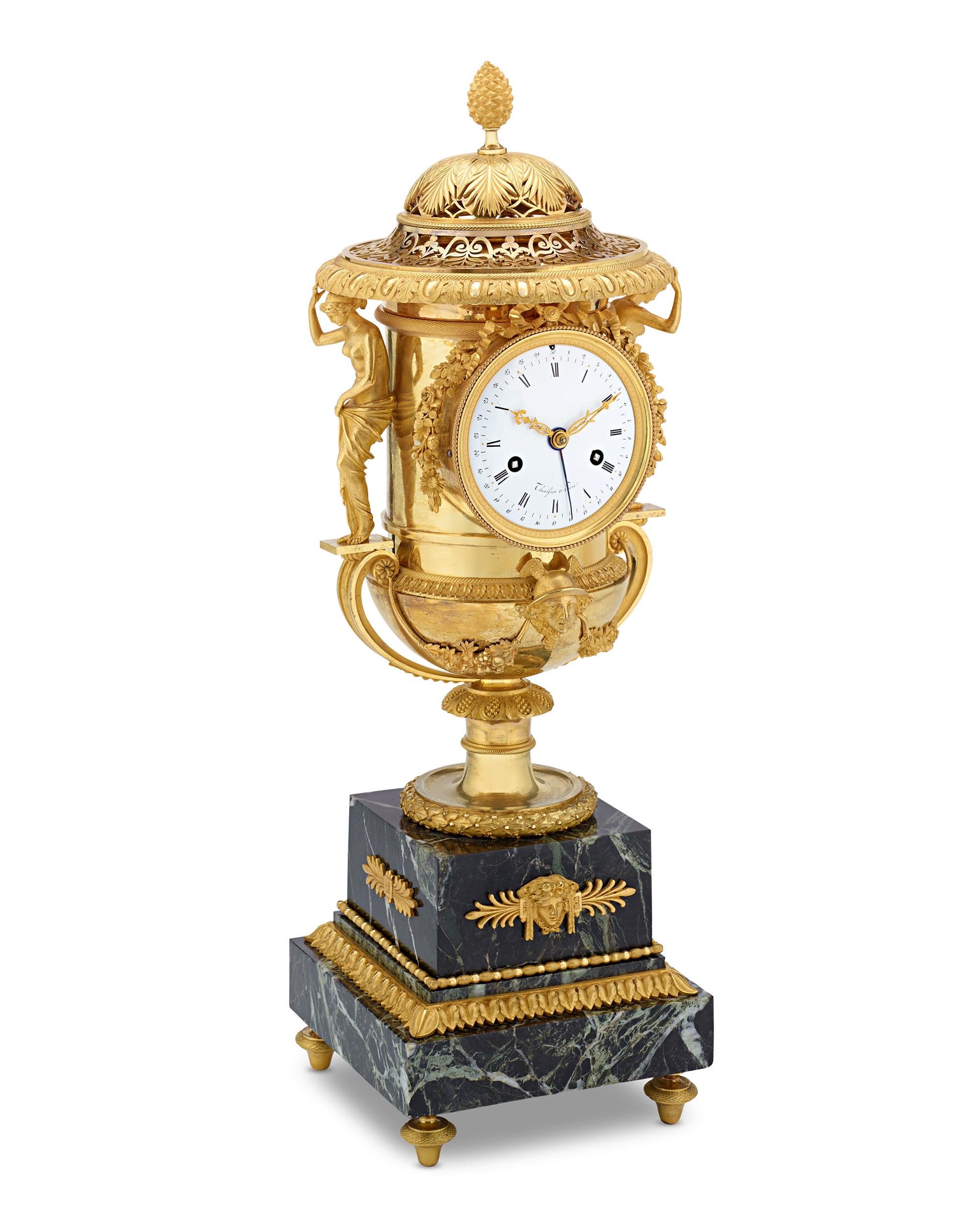 This exquisite Empire gilt bronze and griotte marble Medici vase-shaped mantel clock with urns is attributed to Pierre-Philippe Thomire. The beautiful vase-shaped case with a leaf-shaped pierced domed lid is surmounted by palm fronds and a pine cone