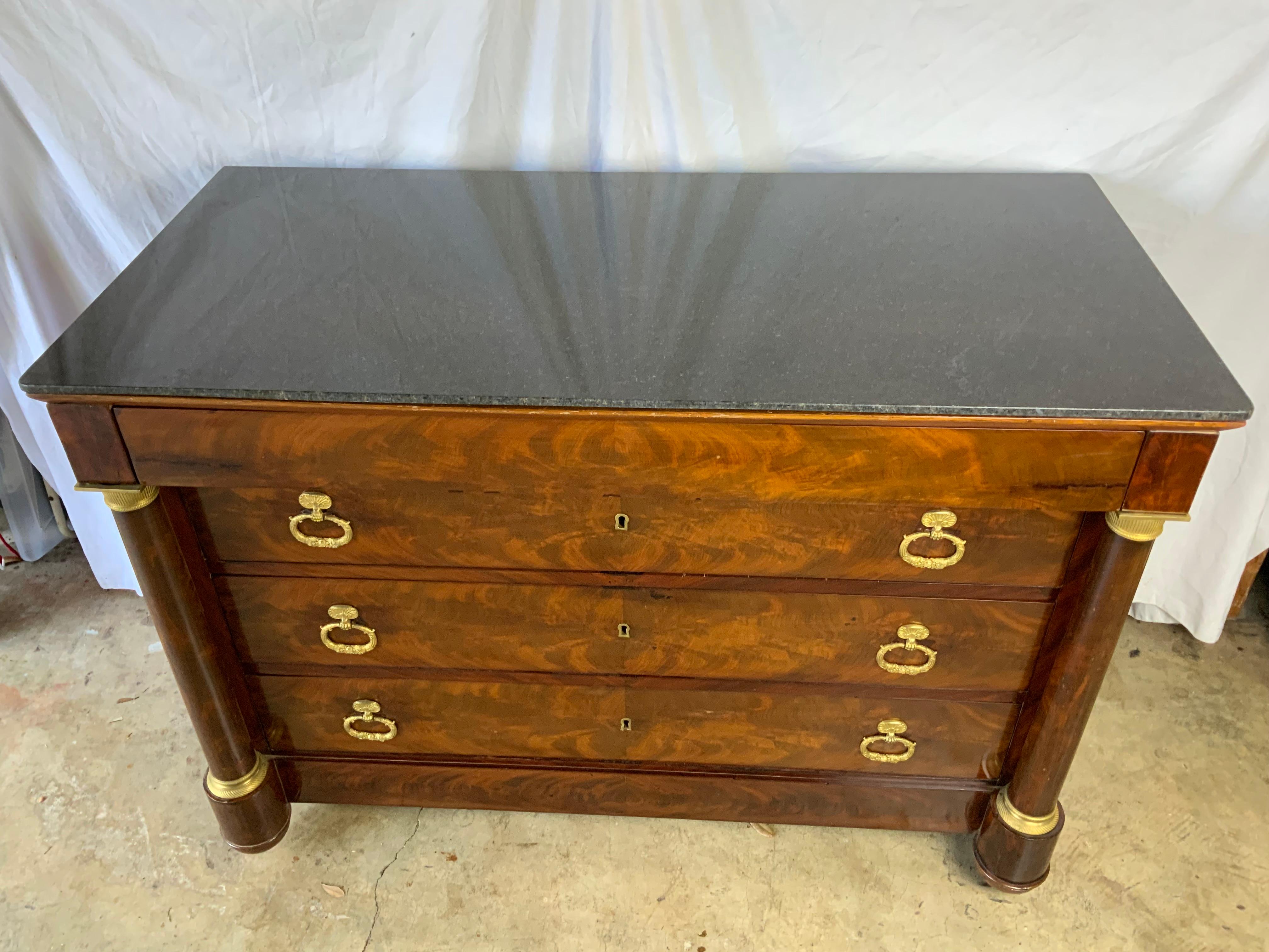 A very attractive French Empire Mahogany Commode.  Solid granite top over 4 drawers all with working locks and individual keys for each drawer.  Round Mahogany veneer columns with Ormolu trim.   Beautiful French polish older finish with a very nice
