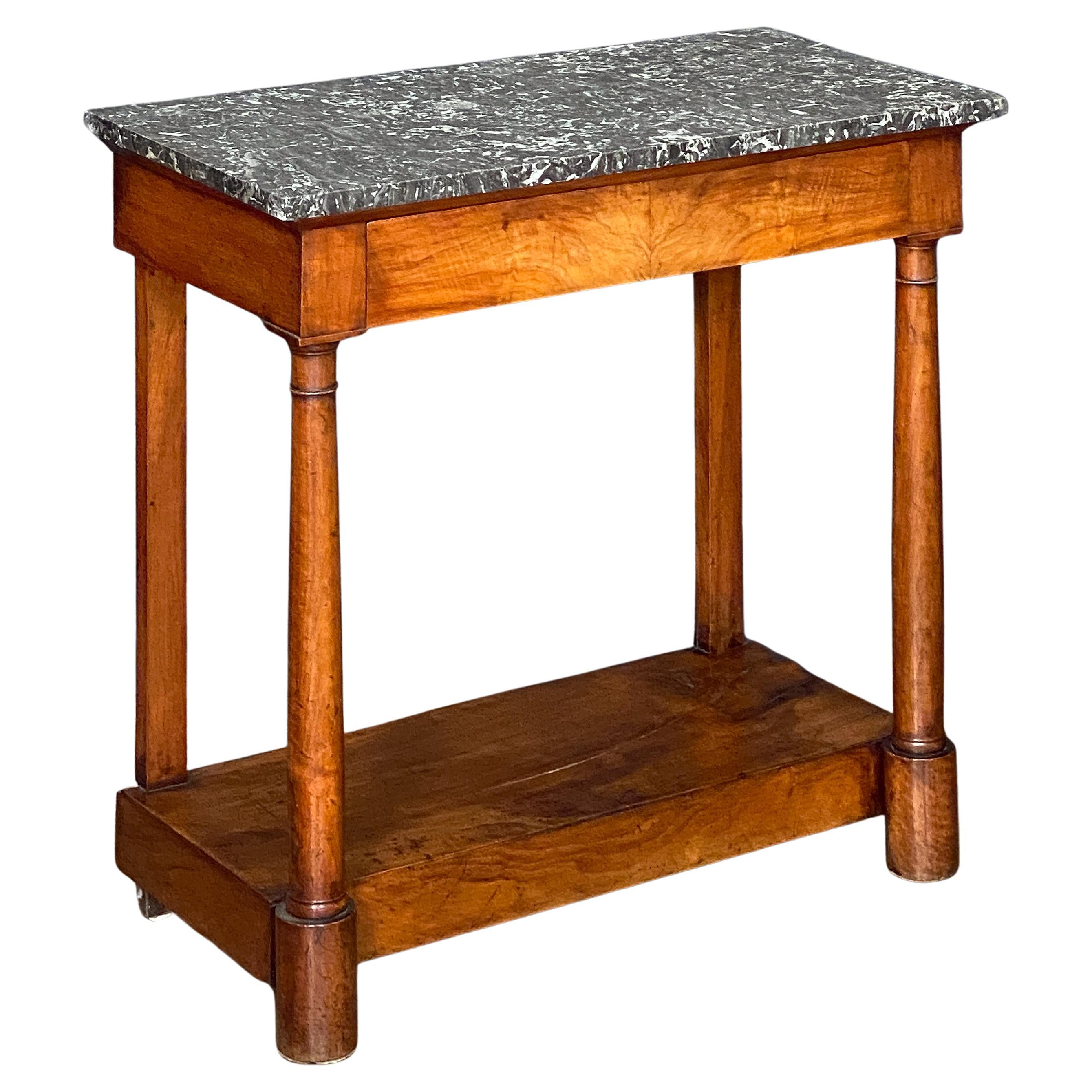 A fine French Empire console table of fine proportions, featuring a rectangular figured marble top, set upon a frieze of flame mahogany with one long hidden drawer over a base with two facing column supports and two backing rectangular supports,