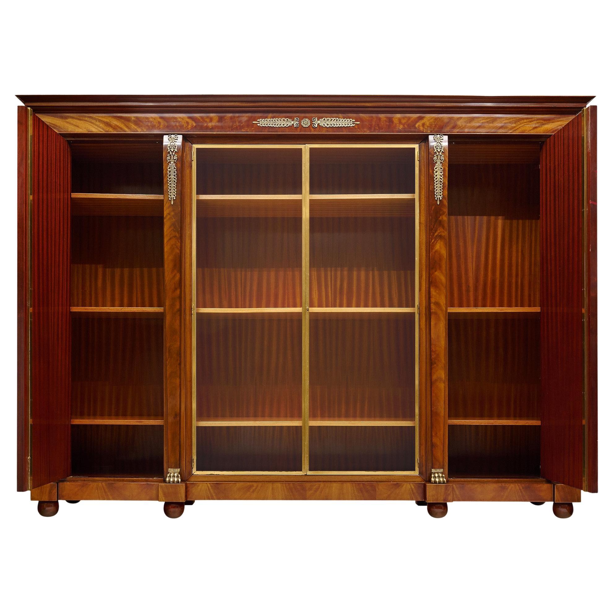 Grande libreria francese in stile Impero. Questo pezzo è realizzato in mogano cubano fiammato e rovere massiccio come legno secondario. Ci sono quattro porte che si aprono su scaffali interni in Wood. Le due porte laterali sono in legno, mentre le