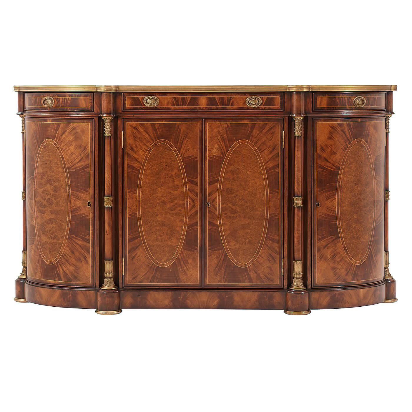 A French Empire style bowfront flame okum veneered and oval pollard oak burl panel inlaid side cabinet or buffet, the brass bound top above three frieze drawers above four cabinet doors enclosing three adjustable shelves, flanked by brass mounted