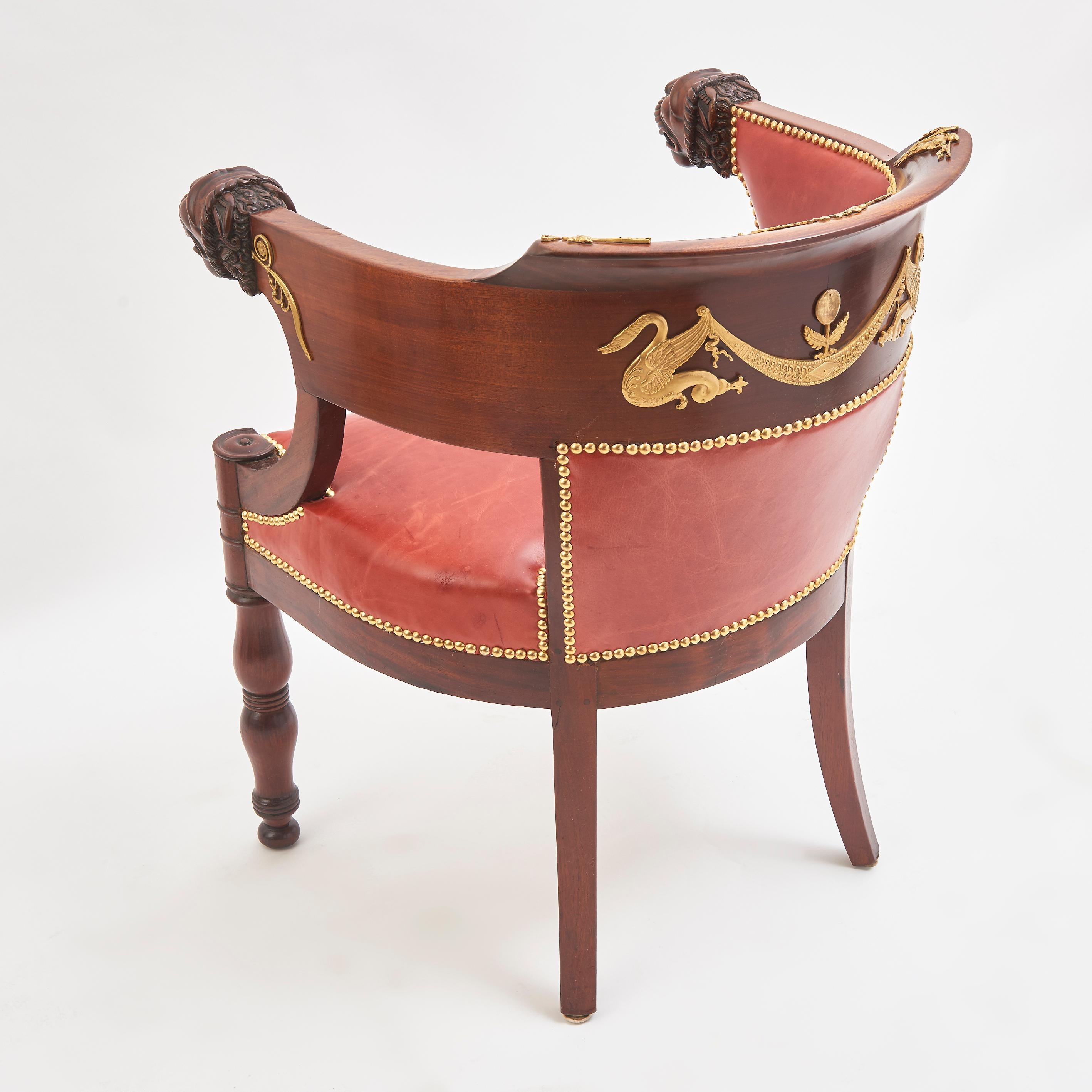 A very fine French Empire mahogany tub desk chair, in the style of Jacob Frères, circa 1830. The curved back terminating in beautifully carved lion's head armrests, above a red leather seat, on ring turned baluster front legs.
 