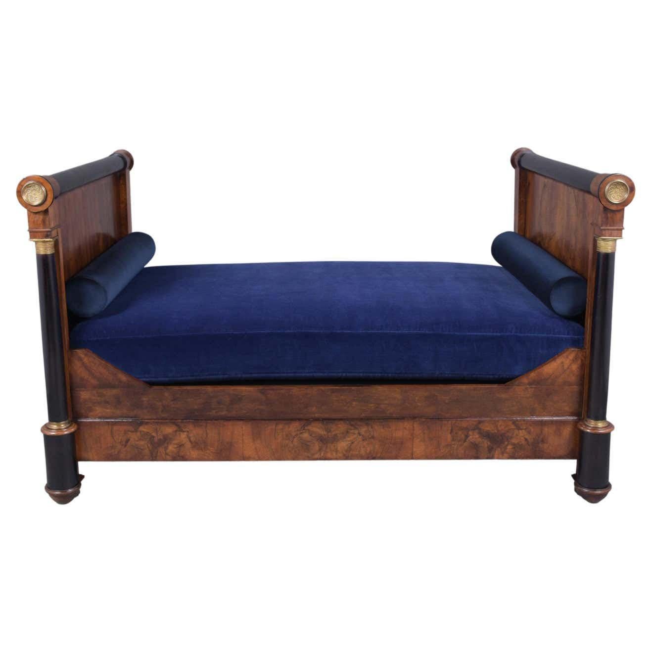 An extraordinary late 19th-century Empire daybed handcrafted out of walnut wood and been professionally restored by our team of in-house craftsmen. This elegant daybed features straight headboard front columns with bronze ornaments, and molding