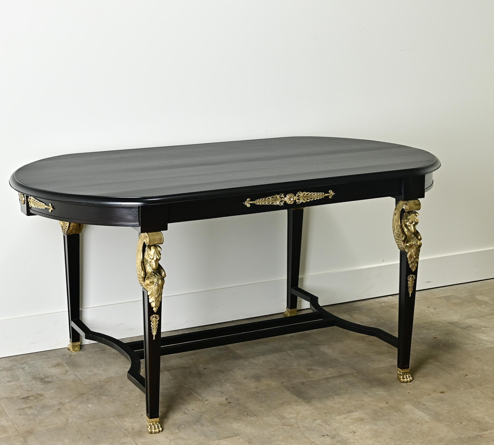 A French ebonized dining table from the Empire period. This mahogany table with curved ends has recently been refinished and ebonized. You’ll find impressive gilt bronze ormolu throughout the table base that has recently been polished. This table is
