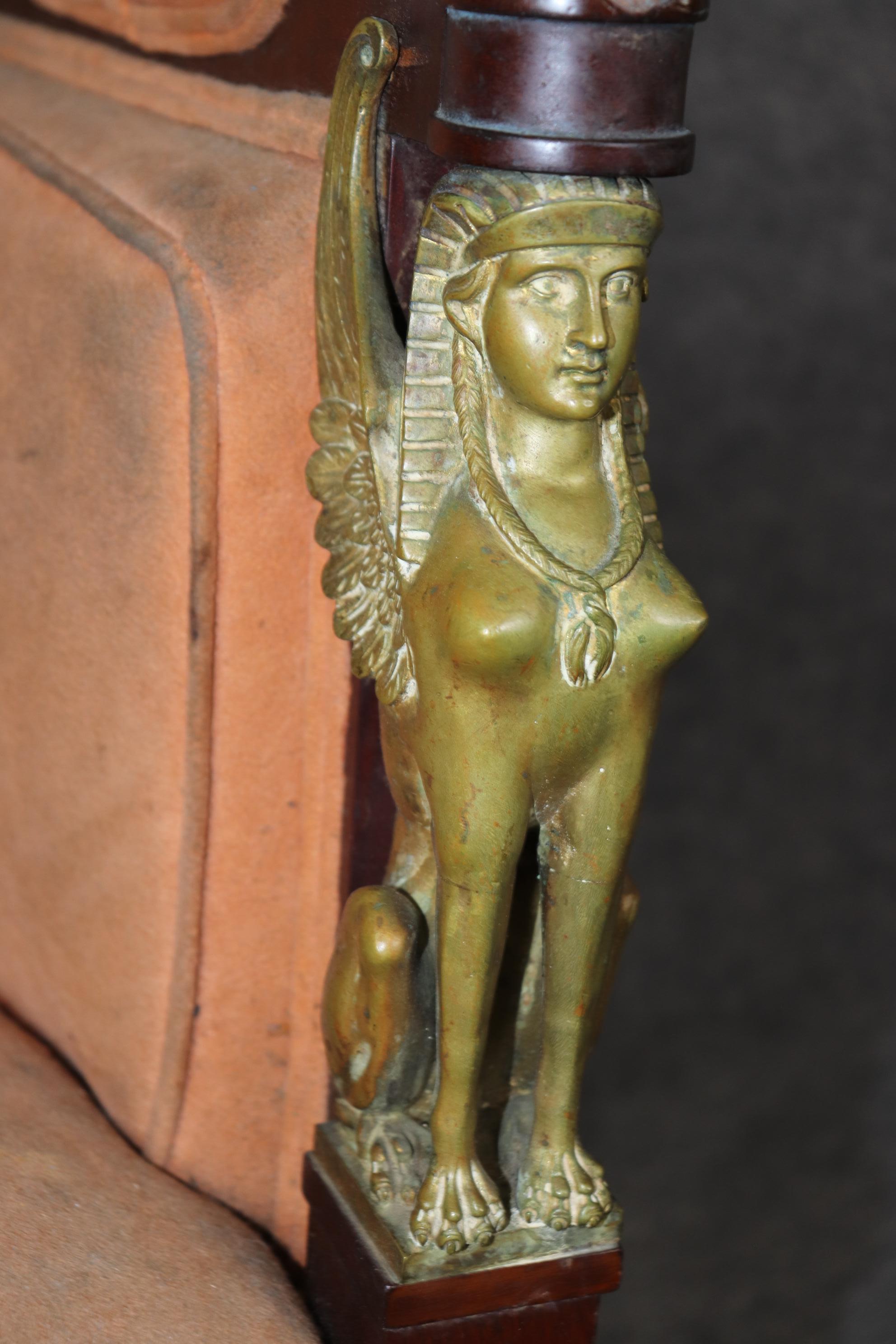 This extraordinary chair is a very rare Egyptian revival or French Empire bergere with solid bronze sphinx figures on each end of the chair and gorgeous bronze ormolu. The chair is in need of reupholstery, and the bronze can be left as-is or