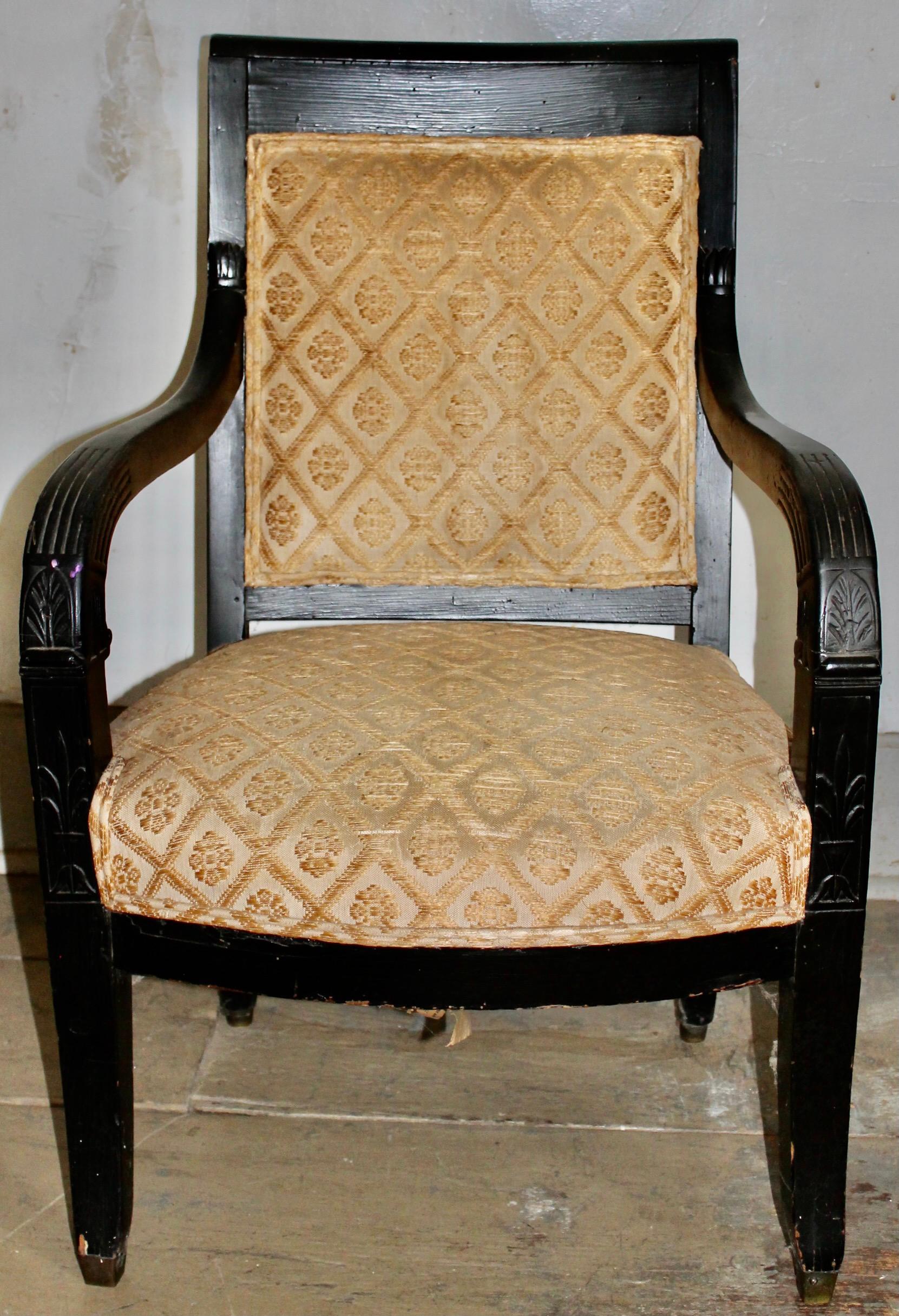 Impressionnant fauteuil noir de forme typiquement Empire français, magnifiquement tapissé. Palmettes subtilement incisées à la jonction des accoudoirs et de l'assise.  Sabots en laiton d'origine. Hauteur du siège 17