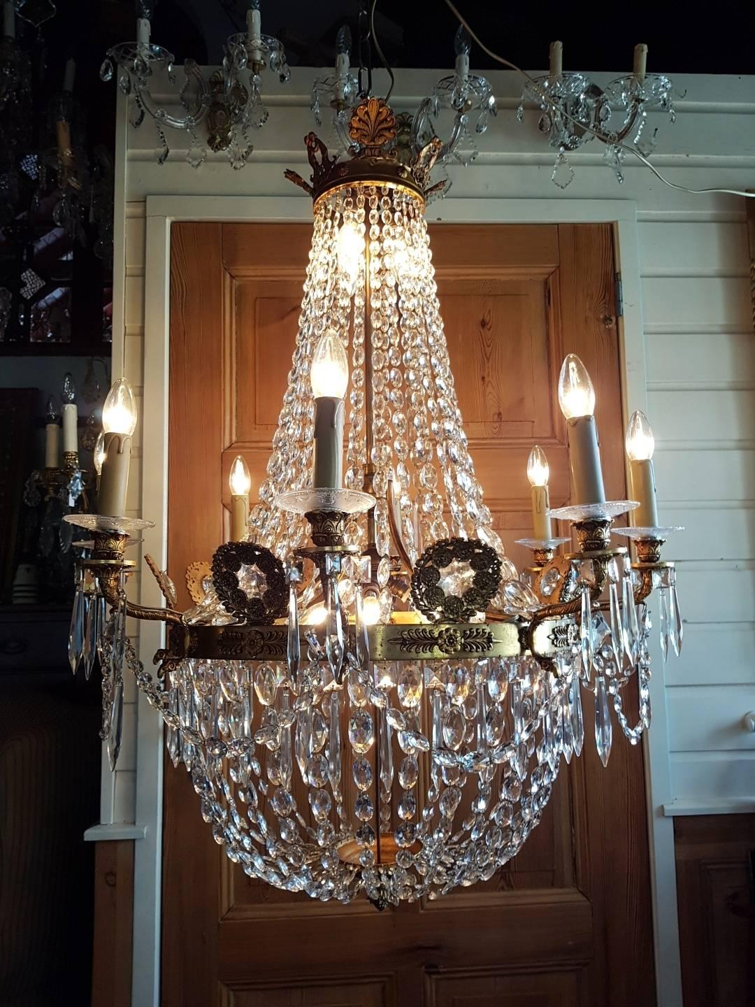 Beautiful empire bronze doré chandelier with hanging strings with oval crystal drops. 15-light crystal chandelier. Eight-lights at the ring, four at the bottom and three at the top beautiful bronze arms and ornaments connected to the middle ring and
