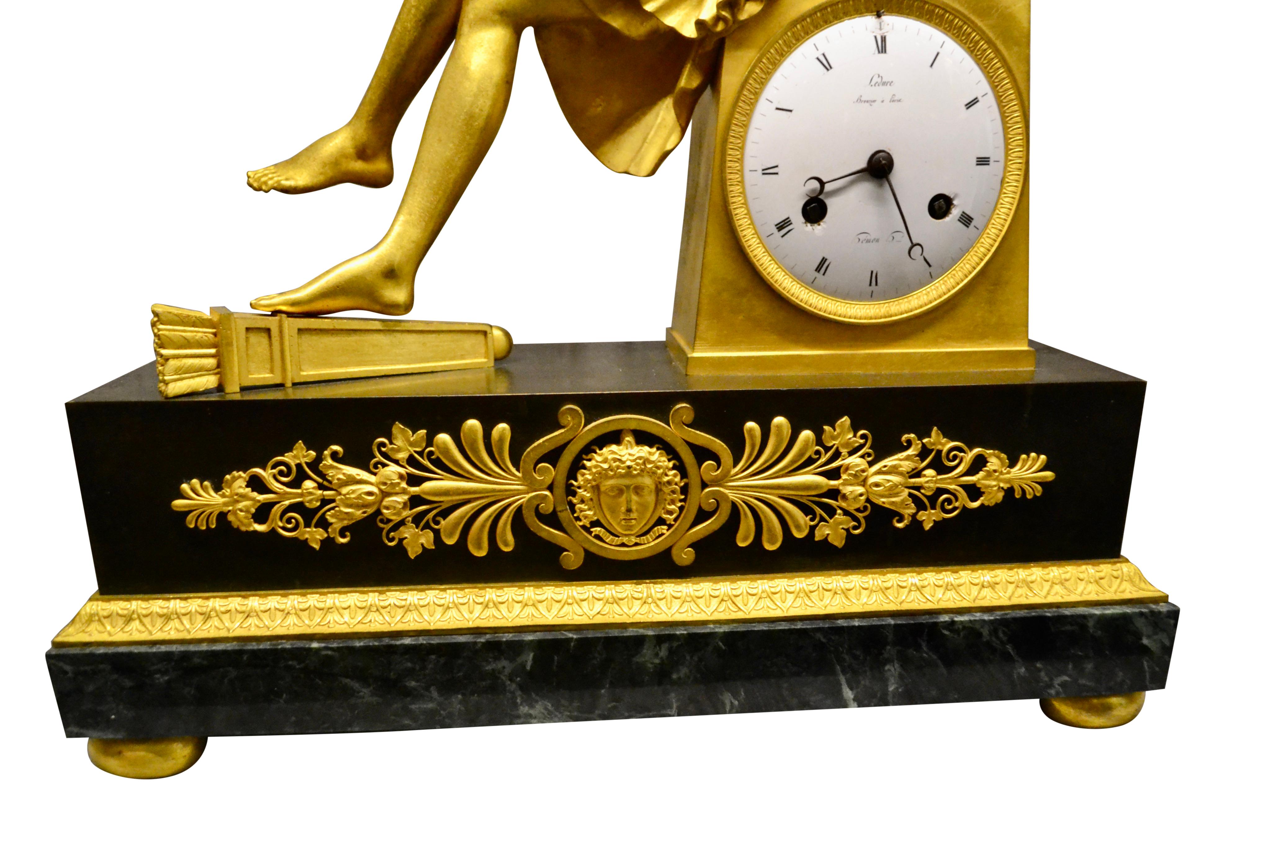 Horloge Empire française en bronze doré et marbre représentant Cupidon assis tenant une rose en vente 1