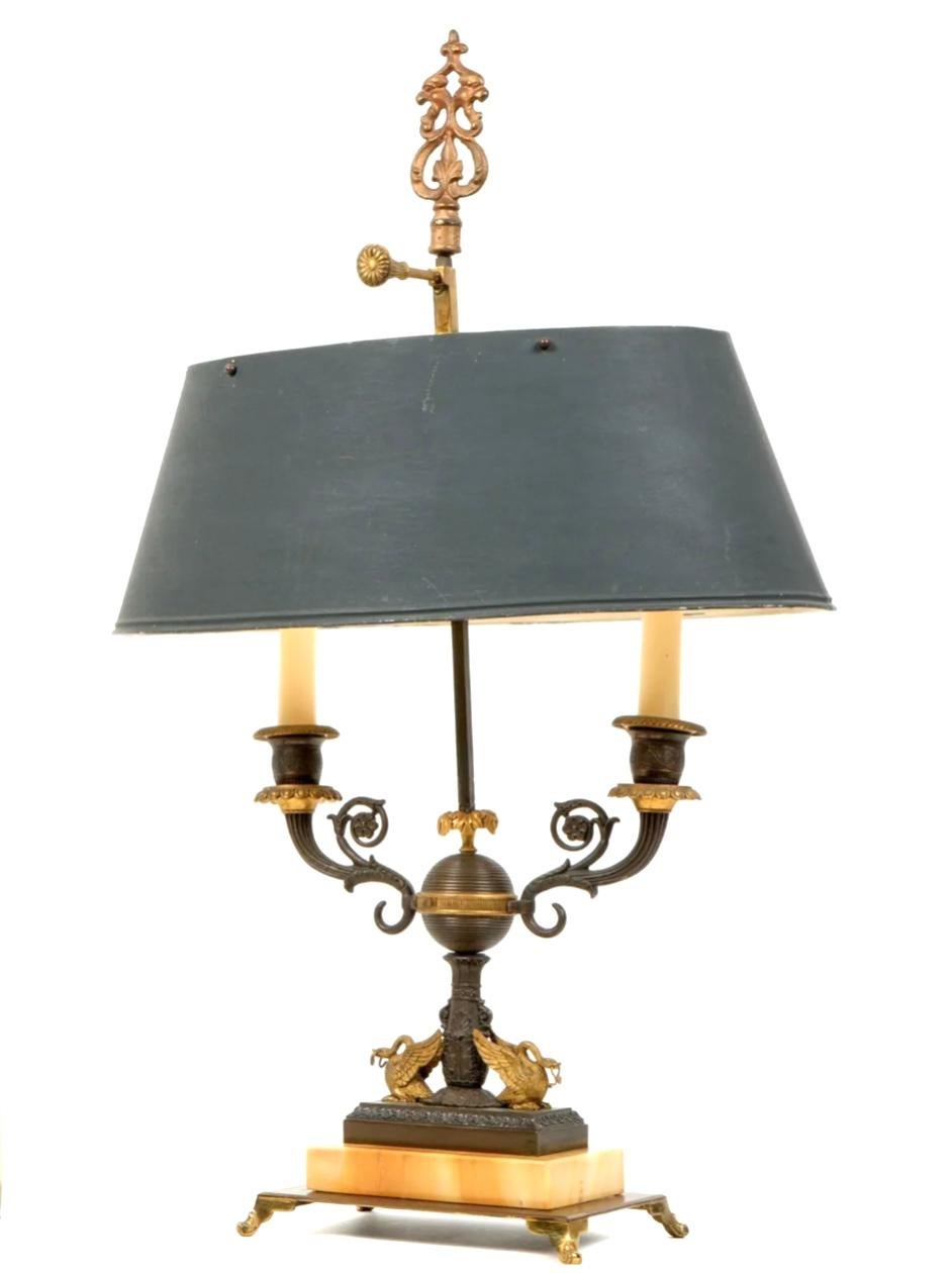 Lampe à deux candélabres, avec abat-jour, de style Empire français du 19e siècle. Base dorée en forme de parcelle, deux bras à enroulement, globe nervuré au centre surmonté de deux cygnes dorés. Marbre sur base en bronze doré, le tout reposant sur