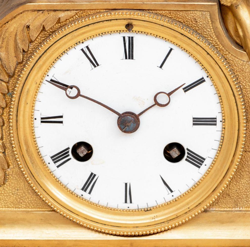 French Empire Gilt Bronze Figural Clock, circa 1840, surmounted by a seated woman resting on a cushion, and holding a dove, circular white enamel dial, the movement strike on bell, on an acanthus scrolled base and feet. 18