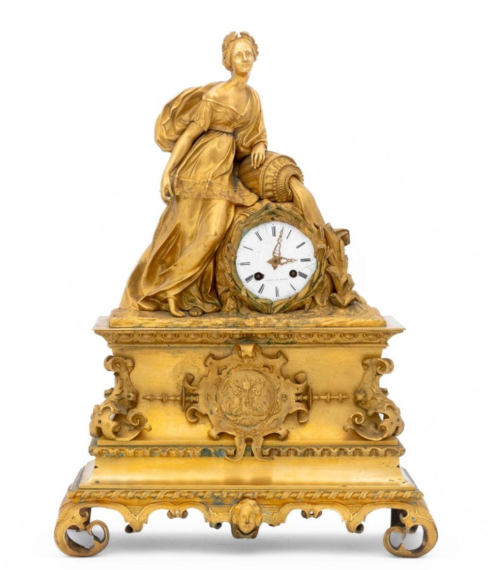 Orologio figurato in bronzo dorato dell'Impero francese, 1830 circa, con quadrante e movimento in smalto bianco su campana sormontata da una figura classica in piedi appoggiata su un'anfora che versa acqua, quadrante firmato 