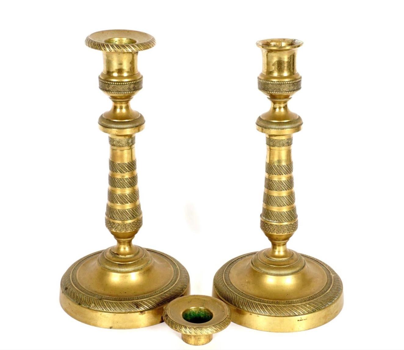 Pair French Empire brass oil lamp candle sticks. Hand blow glass reservoir, brass candlestick style base with bands of stippled and foliate decoration. Original patina. Very rare to find with the glass intact.