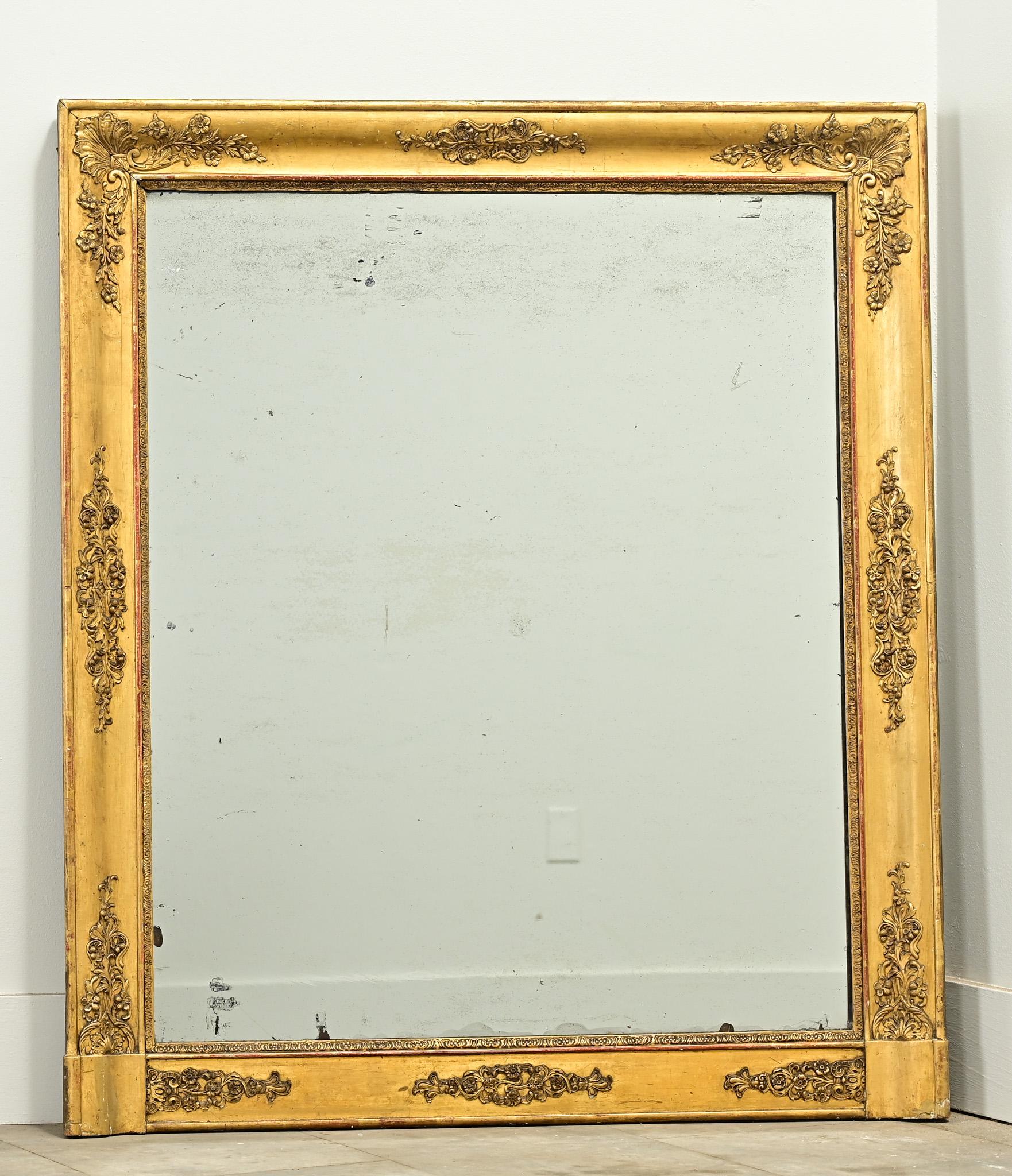 Specchio da camino francese Impero in oro dorato del 1800. La cornice intagliata presenta l'originale finitura dorata che rivela il bolo rossastro sottostante con dettagli decorativi floreali applicati. La piastra a specchio originale presenta