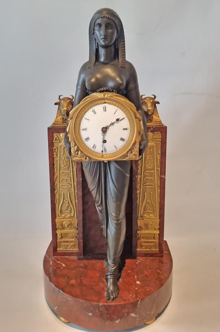 A rare French Empire Gout d'Egypt mantle clock depiciting the Goddess Isis, in ormolu, red or rouge griotte marble and patinated bronze, known as the Thomas Hope Clock. This very rare model was made famous by the Regency designer Thomas Hope, and