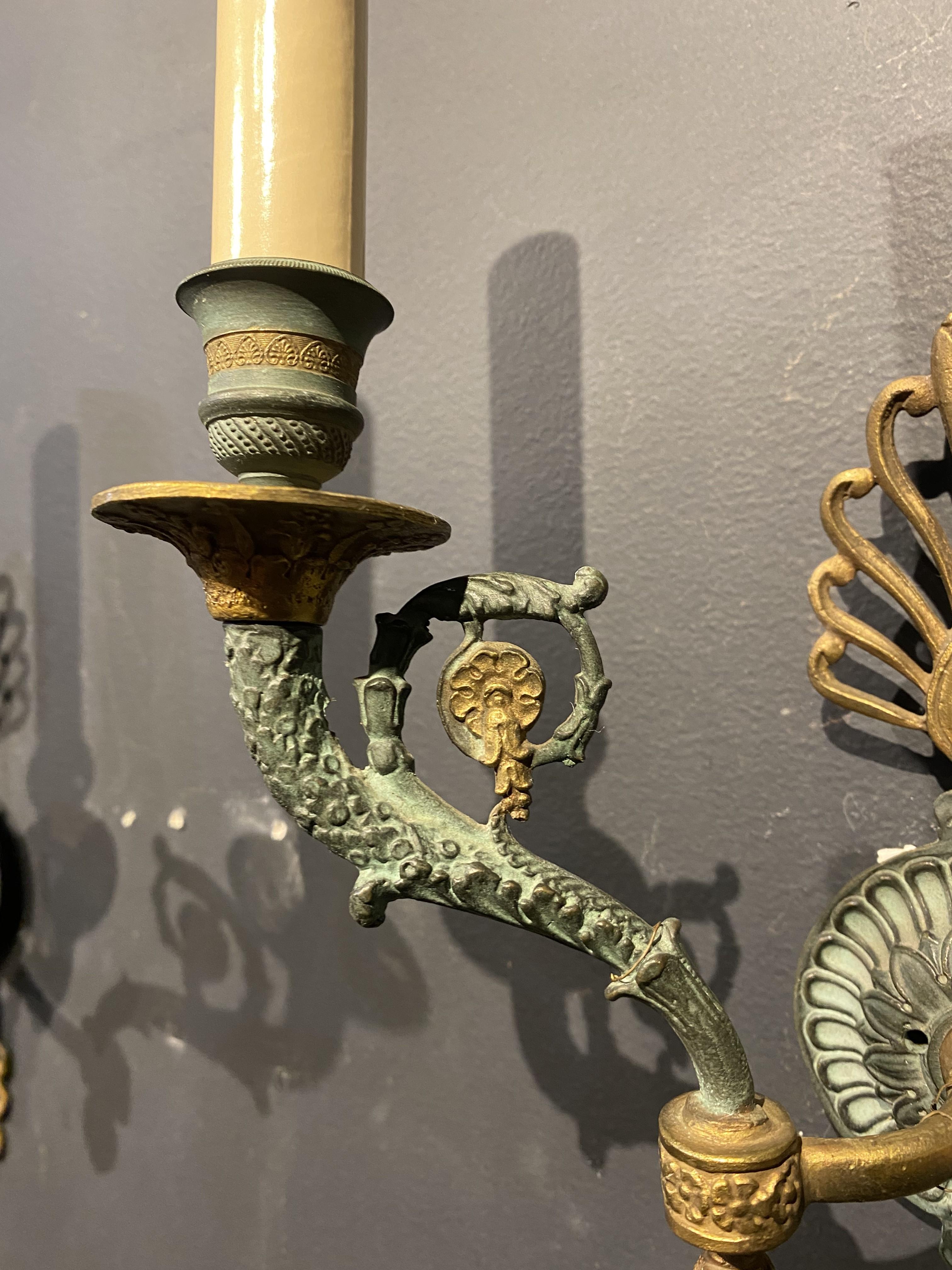 A pair of late 19th Century French empire style double lights sconces, green patinated bronze.