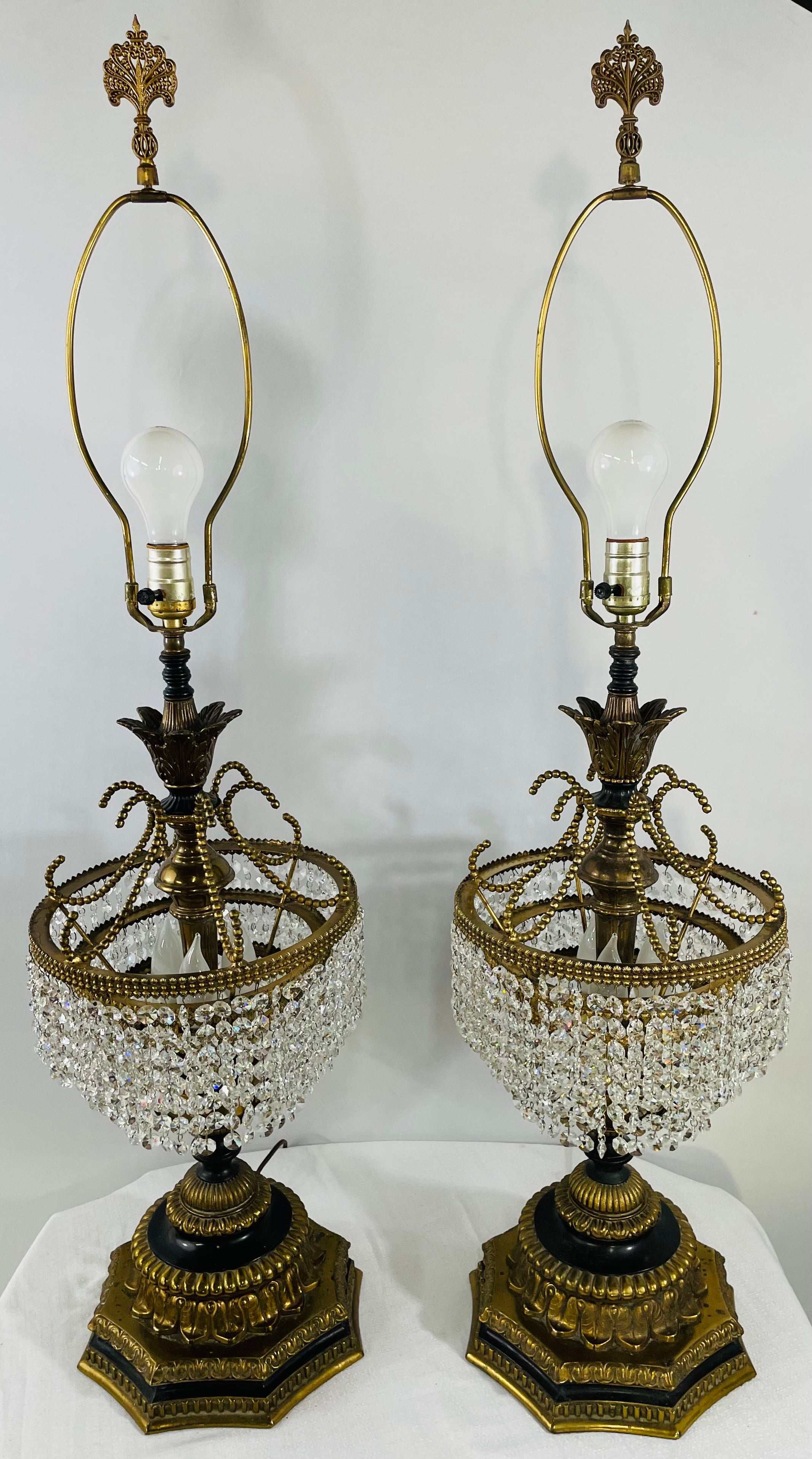 Une paire de majestueuses lampes de table Empire français Hollywood Regency. La colonne de la lampe est sculptée en bronze sous la forme d'une fleur épanouie attachée à un gâteau de mariage à trois étages avec des cristaux clairs. La base