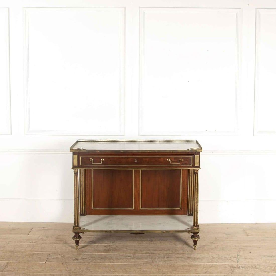 A handsome 19th century French console or serving table in mahogany with inset marble surfaces and brass detailing.