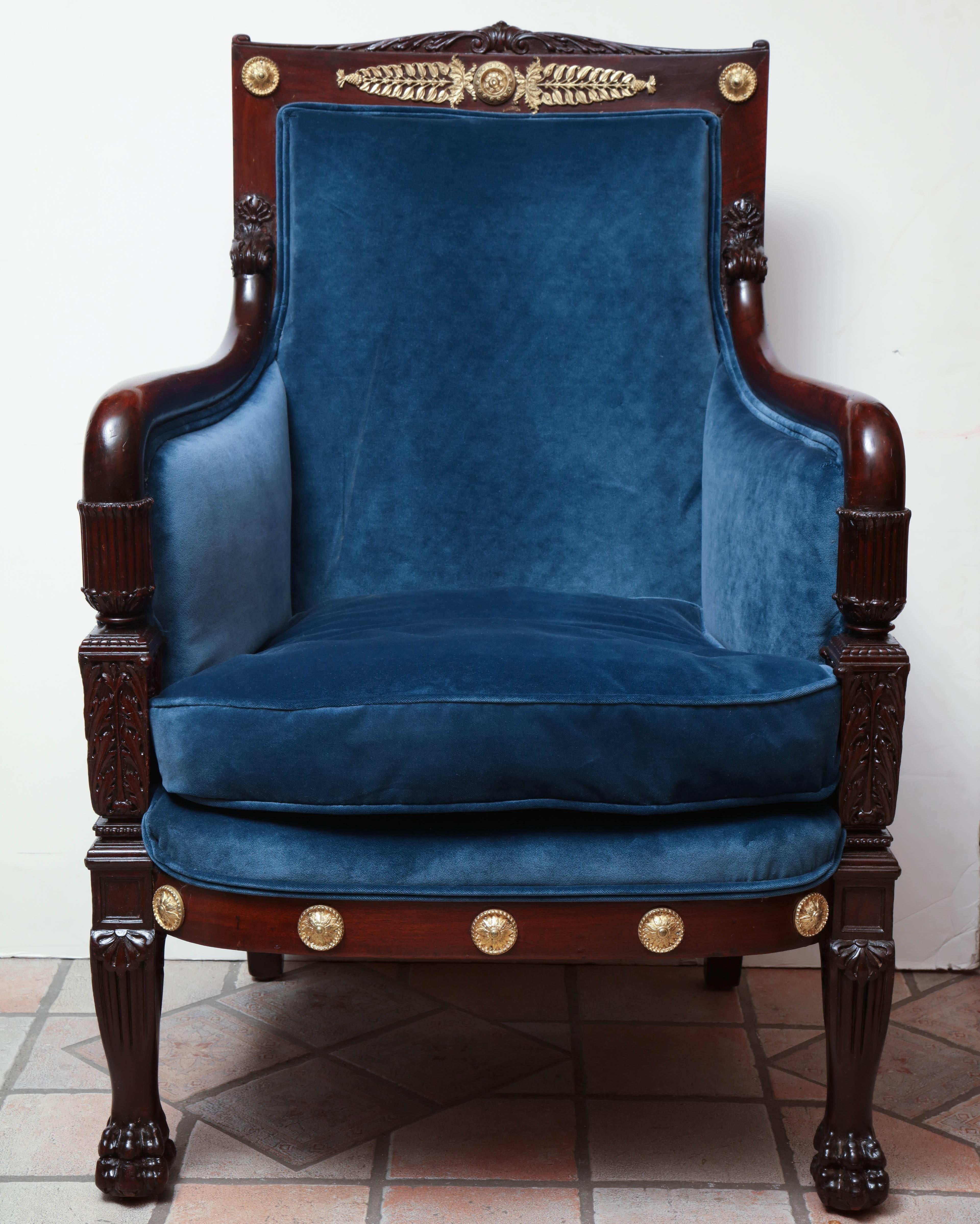 French Empire carved mahogany bergere armchair with bronze mounts and carved paw feet.