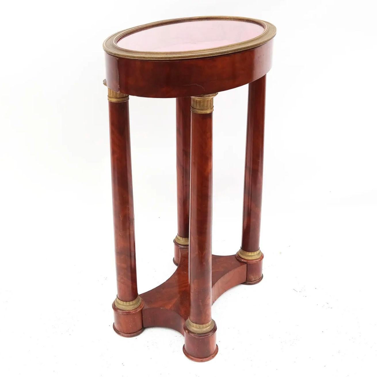 Our exceptional curio table in the French Empire style is crafted from mahogany with engine-turned gilt bronze mounts. Measures: 32 by 23 by 15 inches.