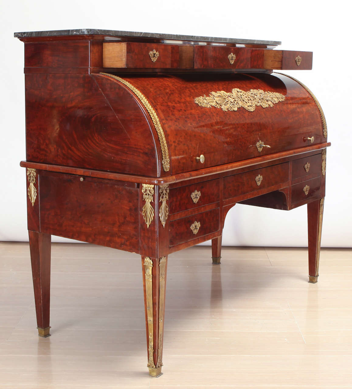 A French gilt-metal mounted mahogany bureau à cylindre writing desk.
With a grey marble top over three drawers, the fall enclosing a sliding tan leather writing surface, an interior with three drawers and with three further pigeonholes, drawers