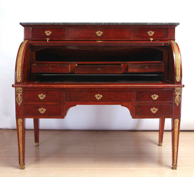 A French gilt-metal mounted mahogany bureau à cylindre writing desk.
With a grey marble top over three drawers, the fall enclosing a sliding tan leather writing surface, an interior with three drawers and with three further pigeonholes, drawers