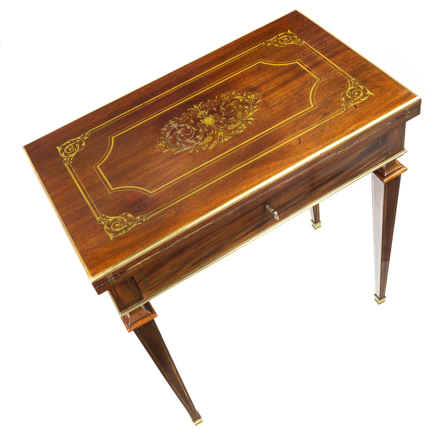 A French Empire combination writing, card table and dressing table. Mahogany with finely inlaid cut brass and a vacant cartouche within an ornate scroll frame, line inlaid borders. The purple felt interior within gilt tooled leather borders, the