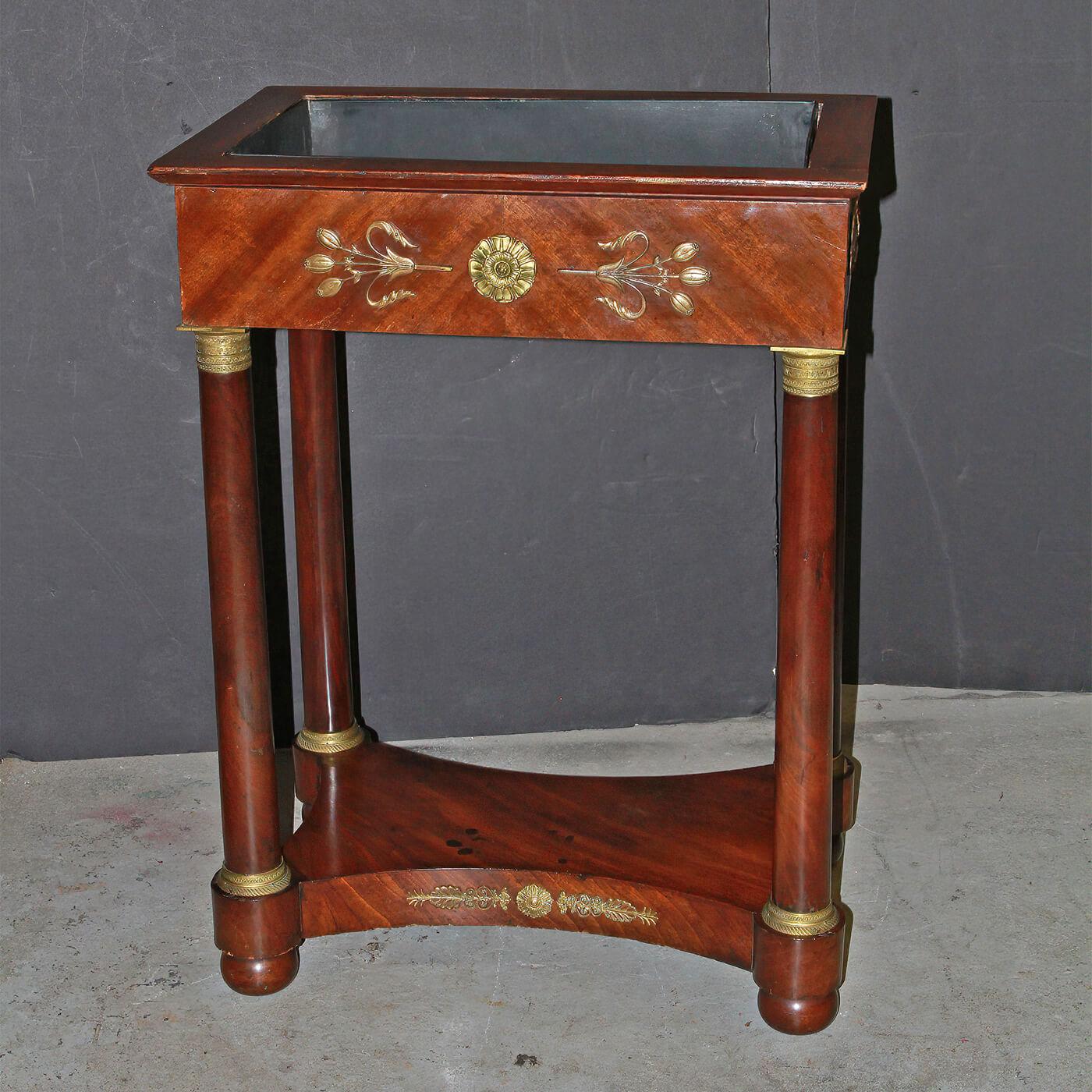 A Frech Empire mahogany bronze planter with bronze mounts, bronze capitals on turned column form legs, with a shelf stretcher. Ca 1820

Dimensions: 25.75