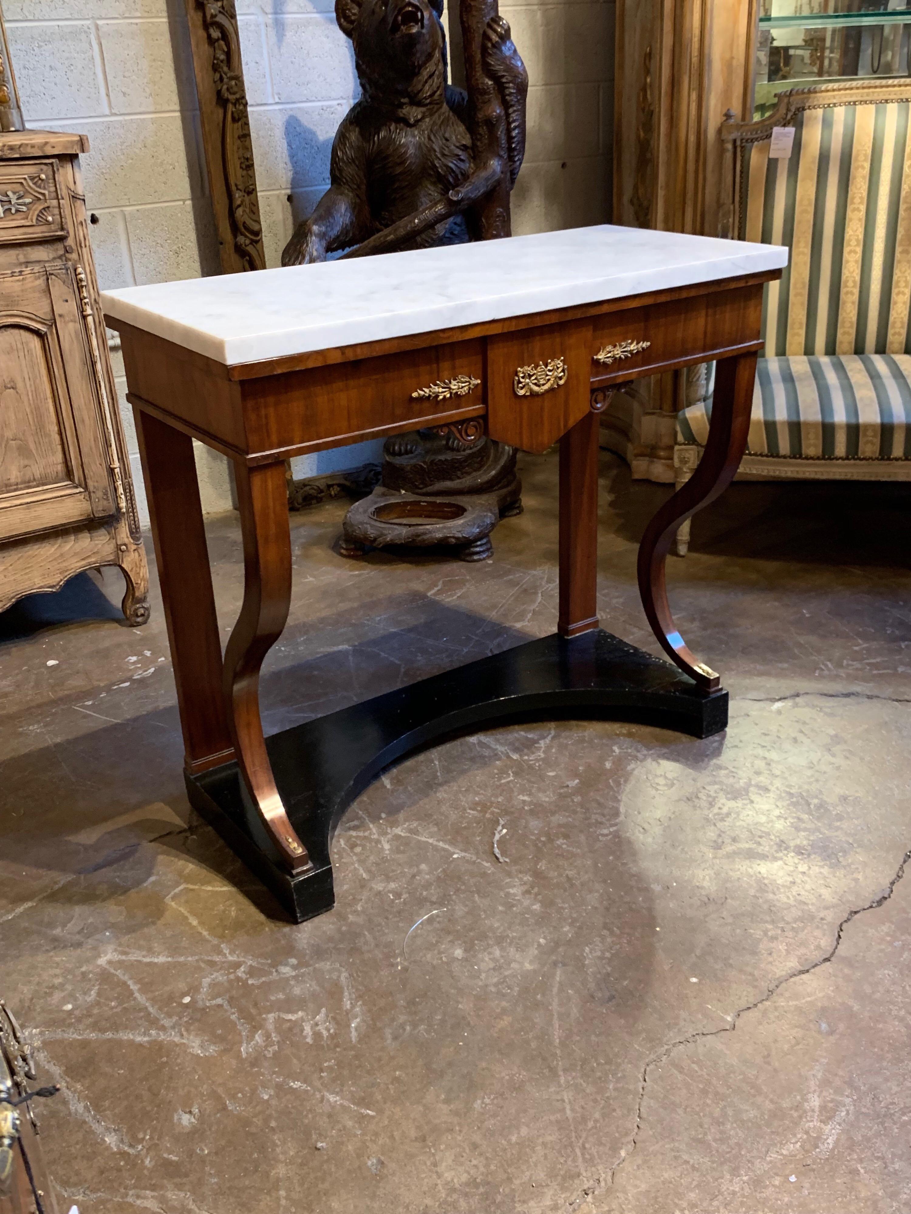 Very fine French Empire mahogany side table with ebony base. There are beautiful brass mounts on the front of the table and the top is made of carrara marble. Exquisite for an elegant home.
