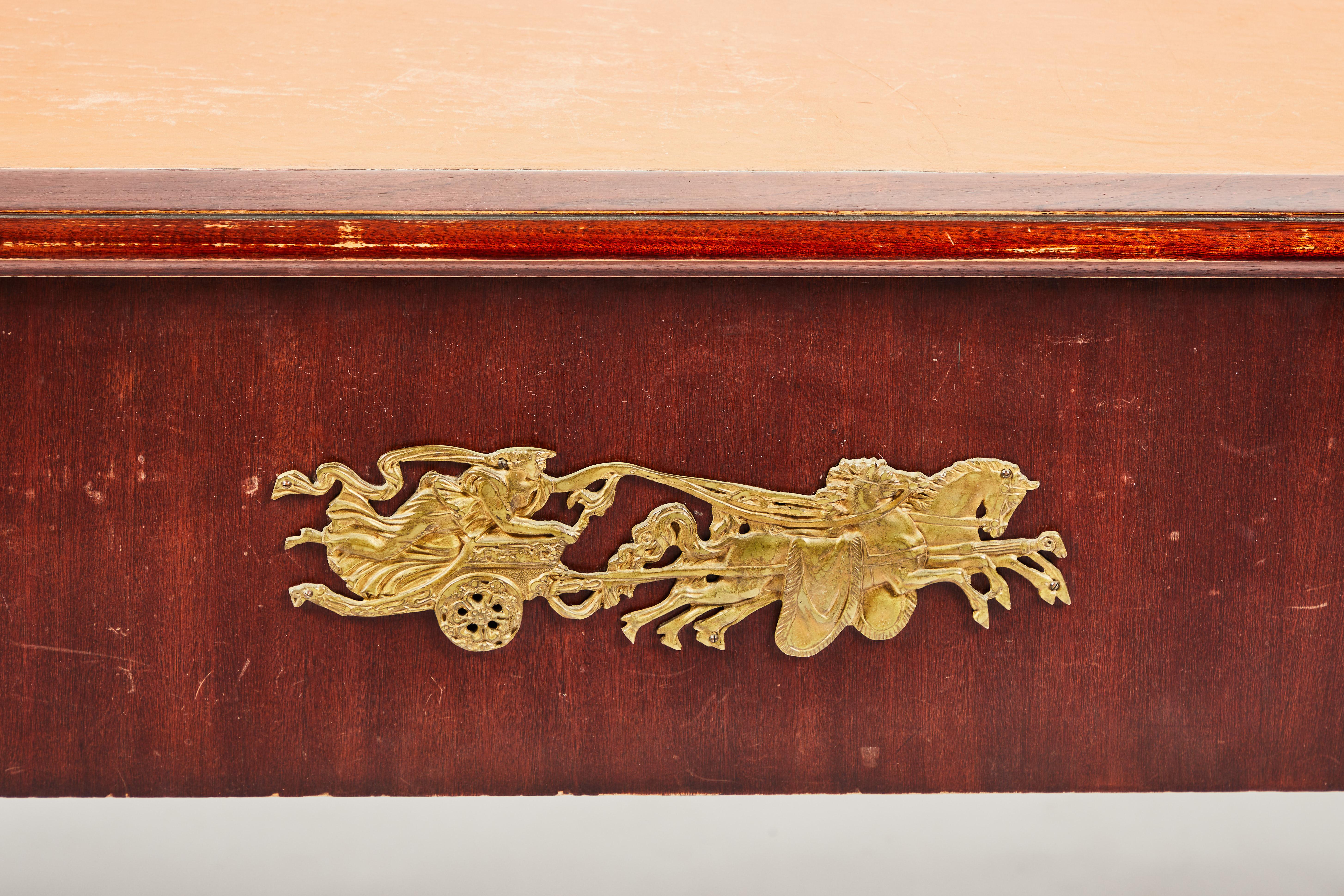 Mahagonikonstruktion mit rechteckiger Lederschreibfläche mit vergoldeten Messingmedaillongriffen. Die Rückseite ist mit einer vergoldeten Metallplakette für einen Streitwagen und ein Pferd versehen. Die Platte ruht auf gedrechselten Bockbeinen und