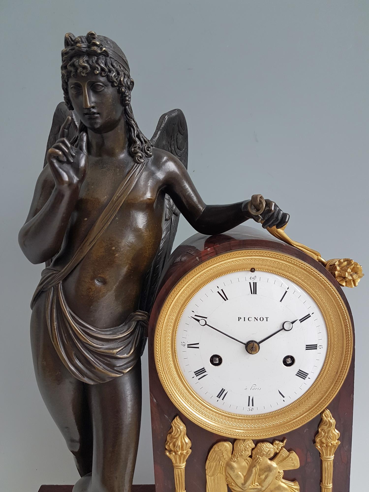 French Empire clock of stunning quality constructed of rouge marble, original fire gilt ormolu and patinated bronze. Set upon four ormolu paw feet to the rouge marble base, rising to the marble case housing the movement, with applied ormolu mounts