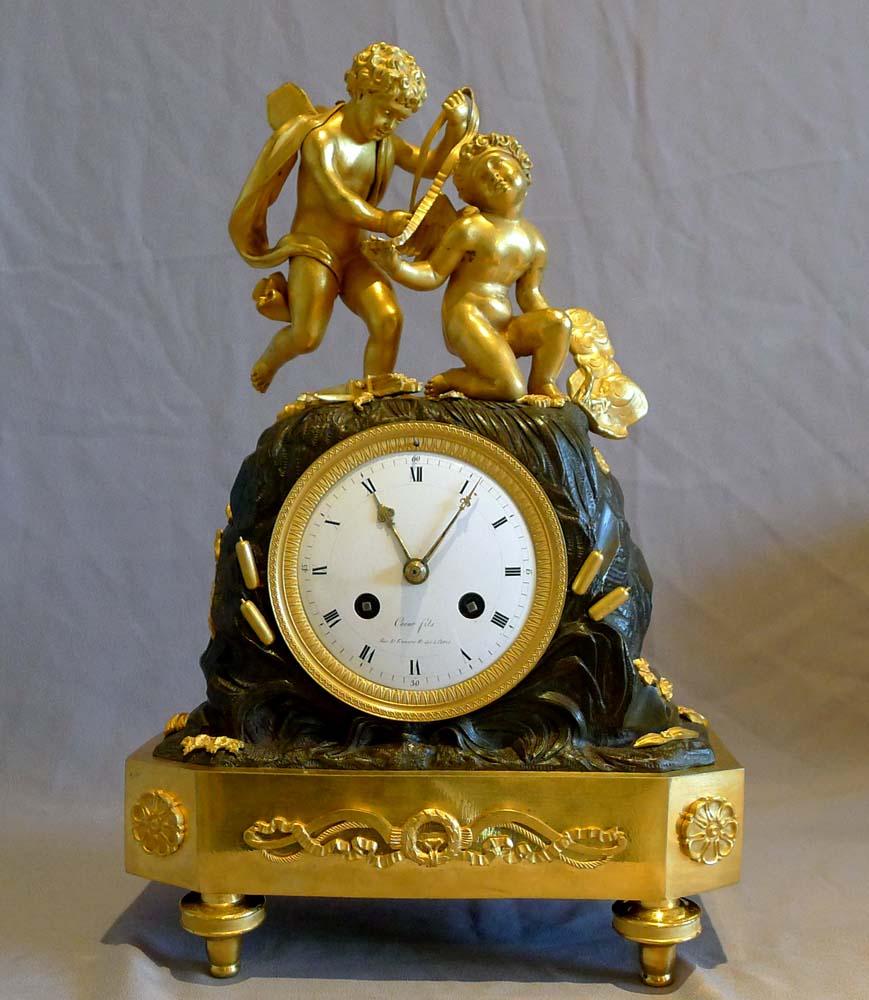 Patinated French Empire Mantel Clock of Two Cupids Signed Coeur For Sale