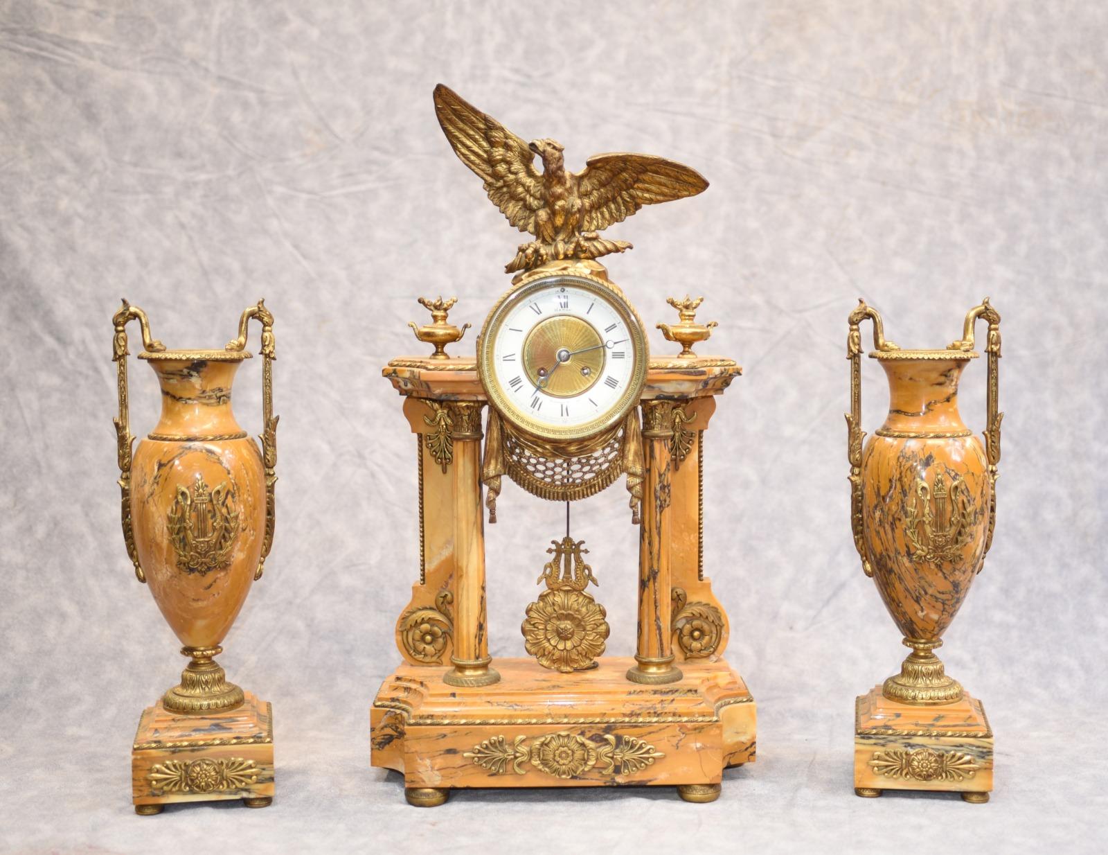 - Stunning French Empire marble and gilt clock set
- Central mantle clock flanked by two urns of amphora form
- We date this stunning work of art to circa 1880
- The first thing that really grabbed our attention are the lovely pink hues to the