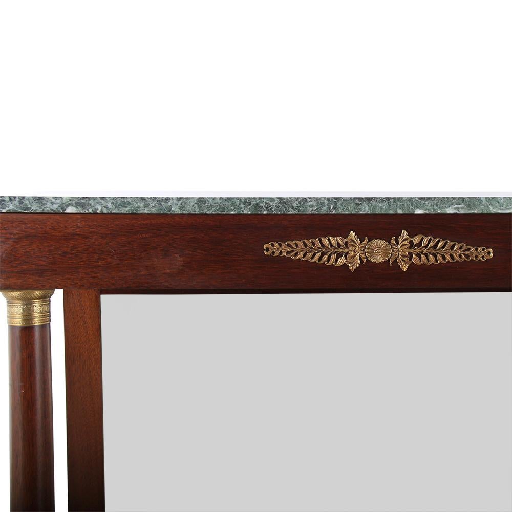 A vintage French Empire-style mahogany console, the two simple columns with brass capitals and bases and raised on a plinth base, the simple geometric top with gilt mounts and a marble surface. 



   