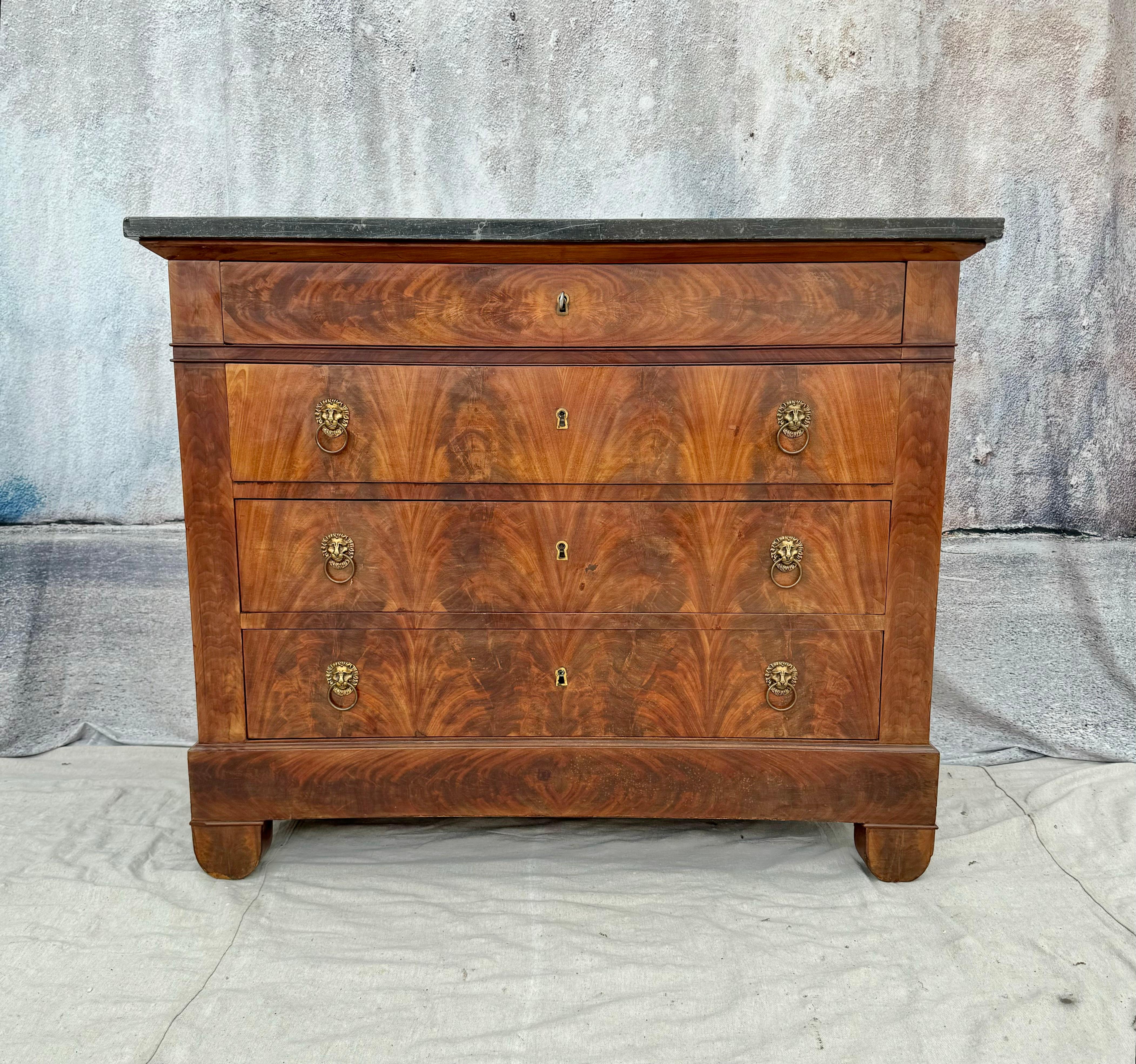 French Empire period marble-top walnut commode, mid 19th century. Commode features brass hardware with lions head handles on four drawers offering ample storage. The strong bold lines and subtle curves of the Empire pieces mix well with other styles