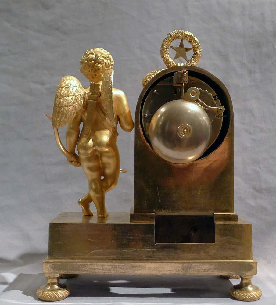 French Empire miniature ormolu clock of Cupid signed by Ledure and Thomas. A small French Empire clock only 10 inches (25 cms high) but of outstanding quality. A figure of Cupid stands on the rectangular base with a bow in one hand and an arrow in