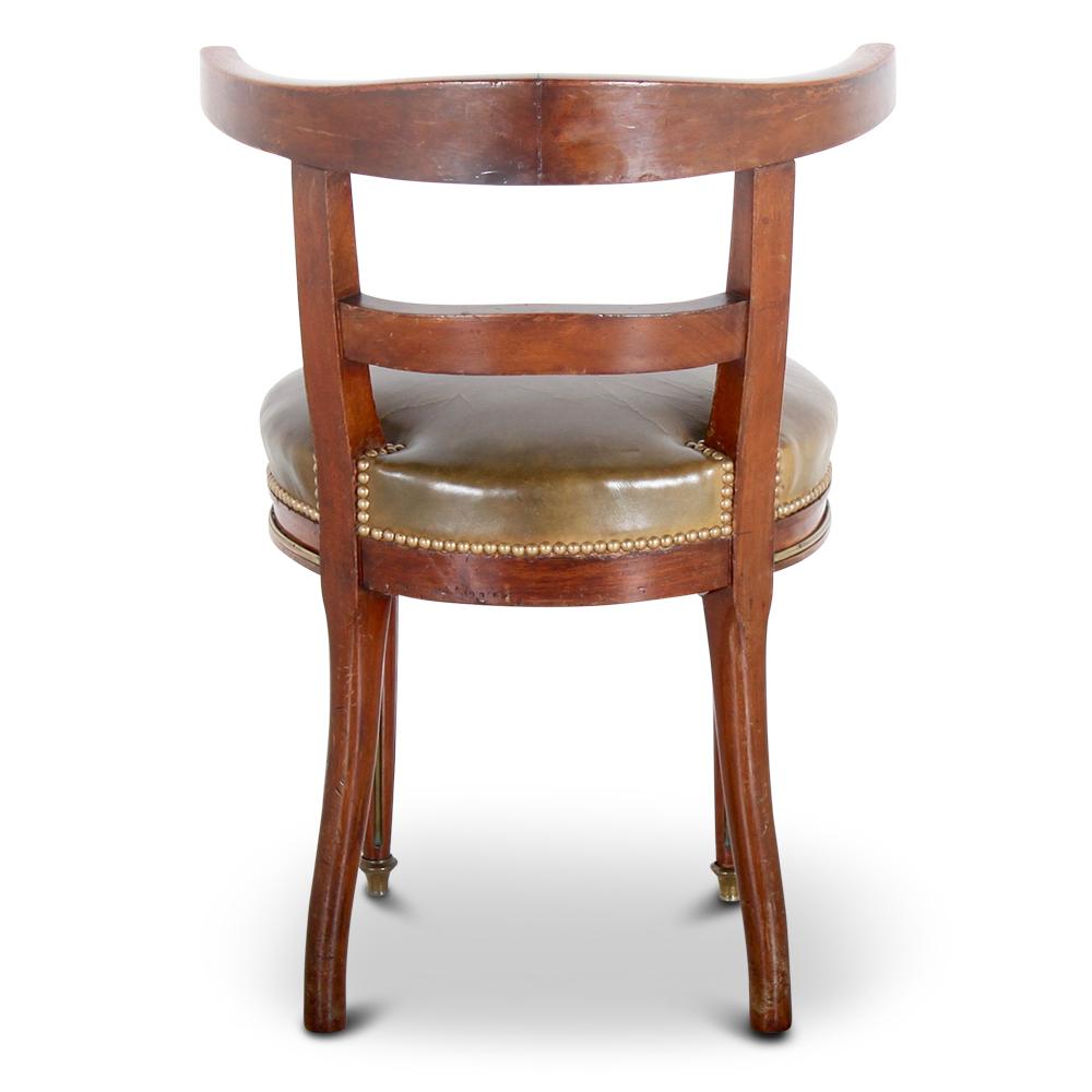 A 19th century French Napoleon III desk or side chair with a round leather-upholstered seat with brass studs, the mahogany frame embellished with brass Empire style details.
The chair is the original match to Napoleon III desk also listed