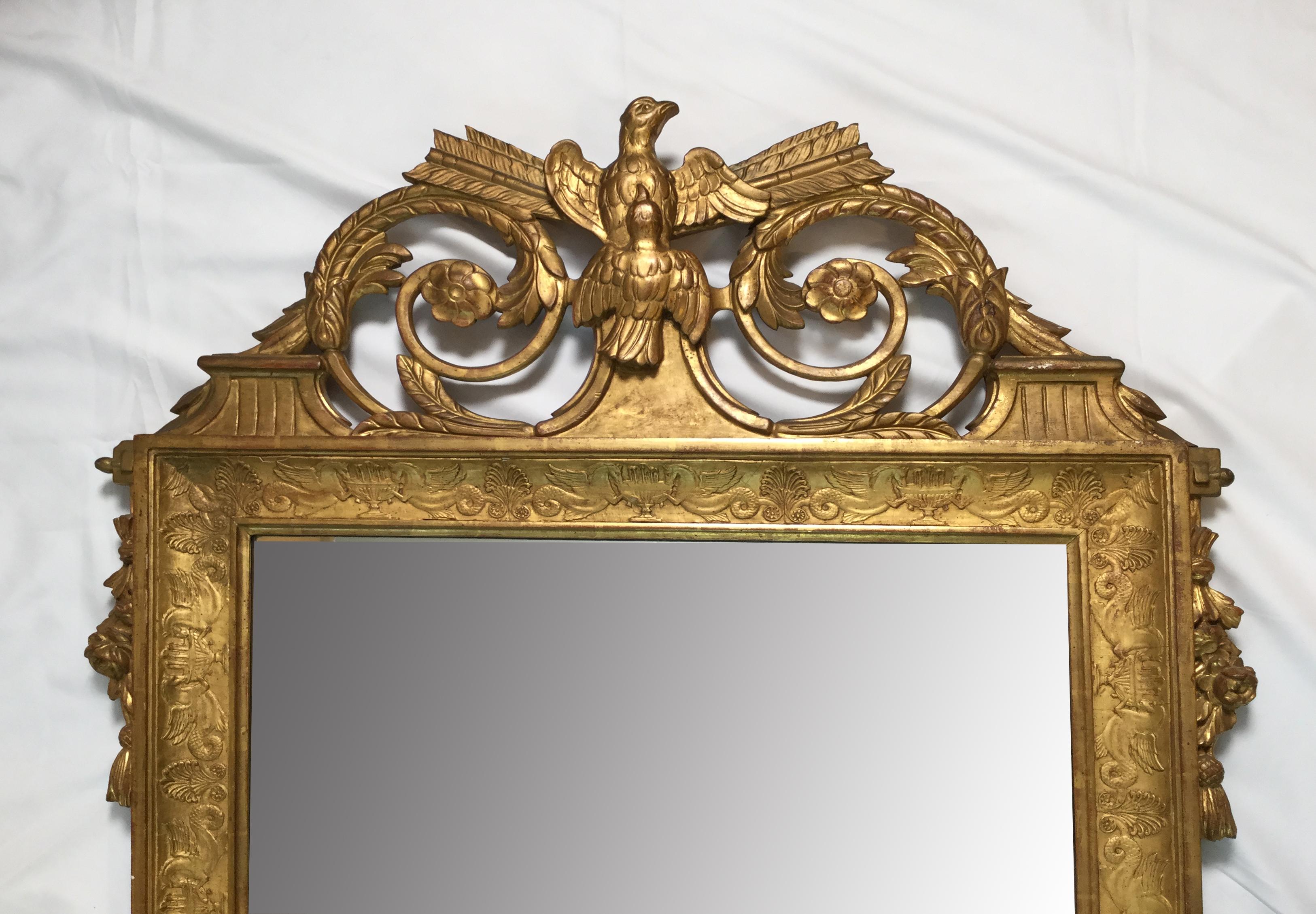 French Empire Napoleonic style giltwood mirror with eagles. A fine giltwood mirror with two ascending eagles on top and intricate figural raised design on the border. Measures: 49' tall by 31' wide.