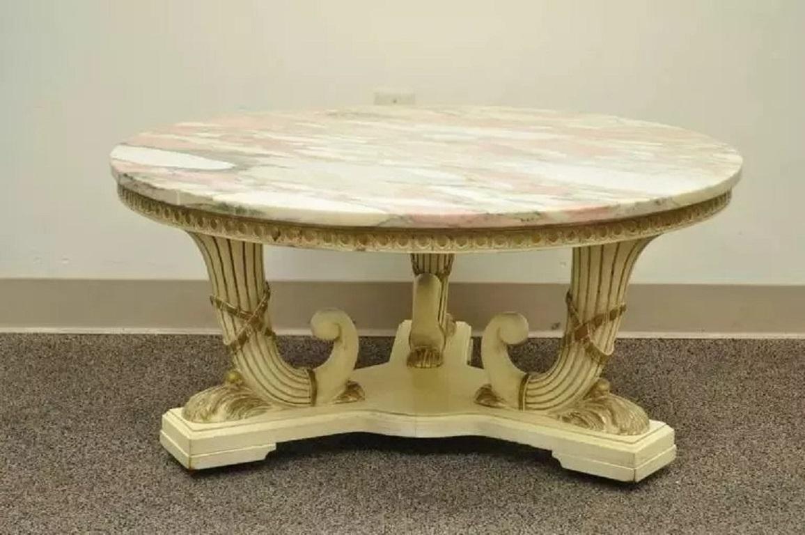 Vintage French Empire Neoclassical Style Marble Top Coffee Table. Item features a triple cornucopia carved wood base, pink round marble-top, off white original painted finish and rolling casters. Circa Mid 20th Century. Measurements: 17.5