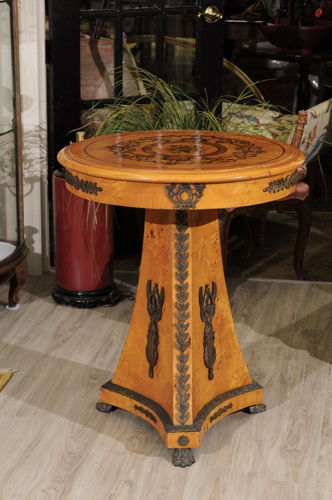 A lovely bird’s-eye maple occasional table with scroll and flower marquetry on the top.
The apron and stand are highly decorated with ormolu mounts. It stands on 3 bronze paw feet.