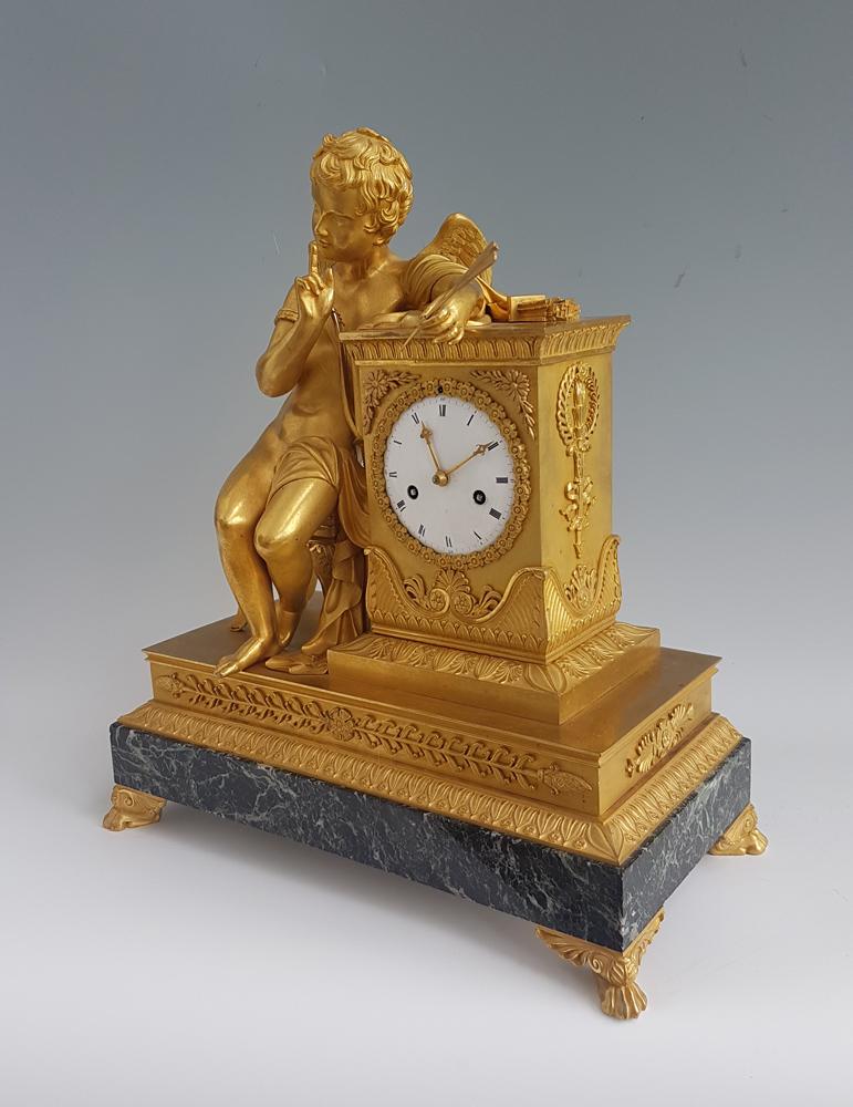 French Empire Ormolu and marble vert mantel clock of Cupid whispering. Wonderful original fire gilded mercury ormolu. The quality of the casting and chasing is superb, from the individual strands of cupids hair, to the tassle on the seat. Cupid sits