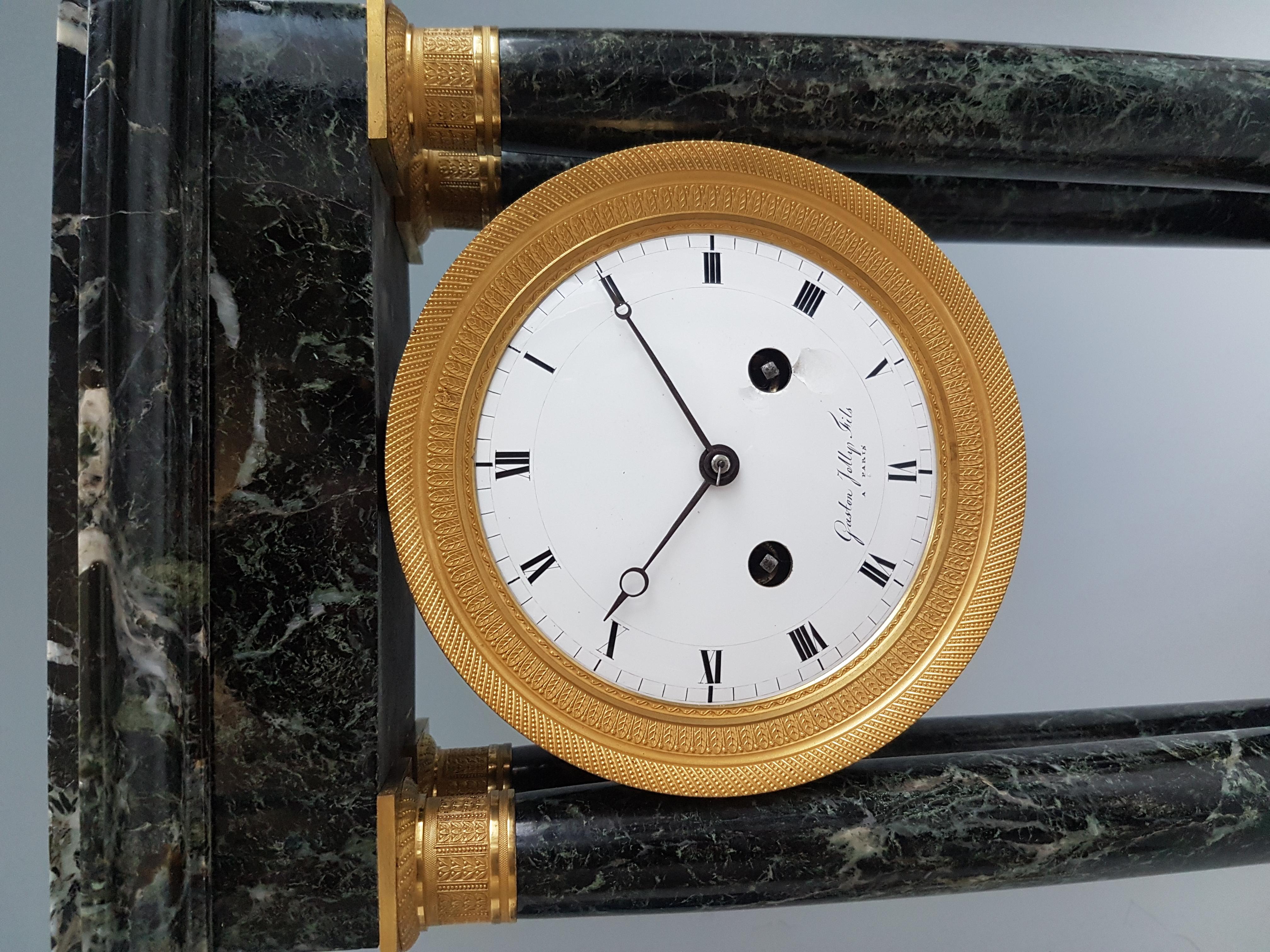 A fine French Empire ormolu and griotte marble portico clock signed Gaston Jolly. Set upon four ormolu bun feet, the four marble pillars have Fine omolu mounts to the top and bottom. The white enamel convex dial, with roman numerals, and breguet