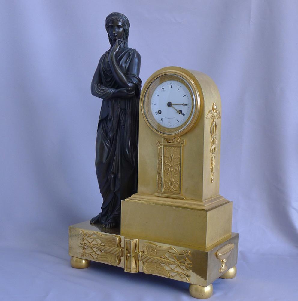 Superb quality French Empire ormolu and patinated bronze mantel clock in a beautifully restrained case. The casting and gilding of the finest quality. A classically dressed maiden stands to the right of the clock housing. Applied ormolu mounts