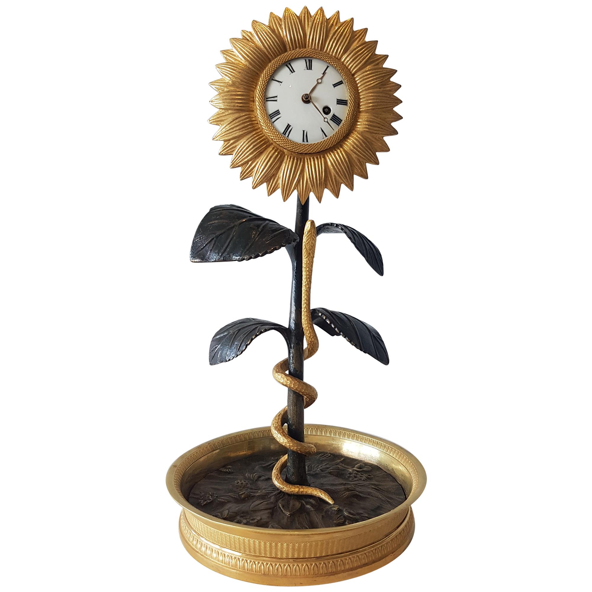 A sublime French Empire sunflower clock in original fire or mercury gilt ormolu and patinated bronze. Wonderful detail in this sweet clock, from the detailed ormolu base, the patinated bronze center showing flowers, to the snake, curling its way up